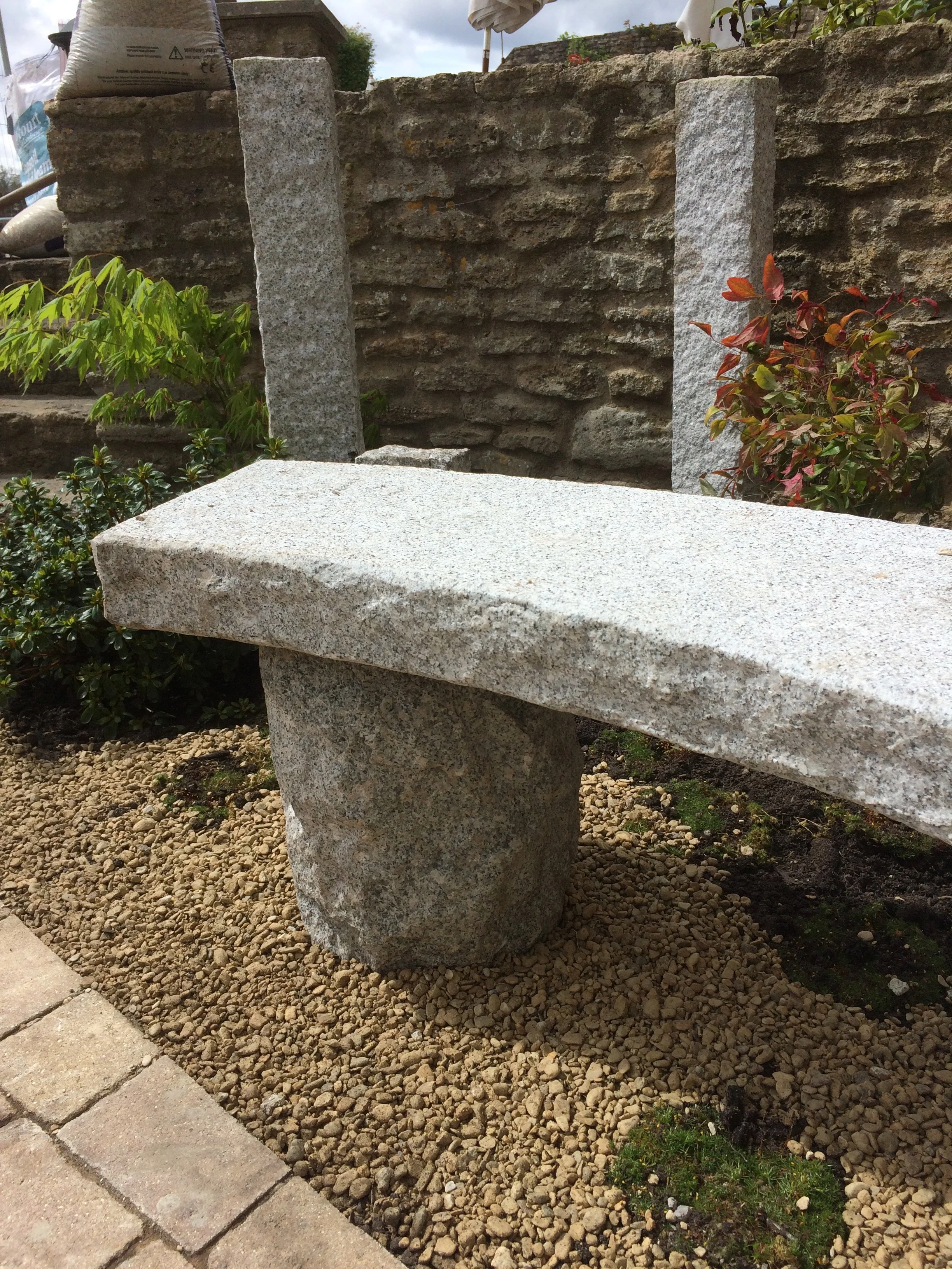 A curved granite bench creates a strong sense of space, guarded over by the palisade stones with moss like Sagina creeping below.