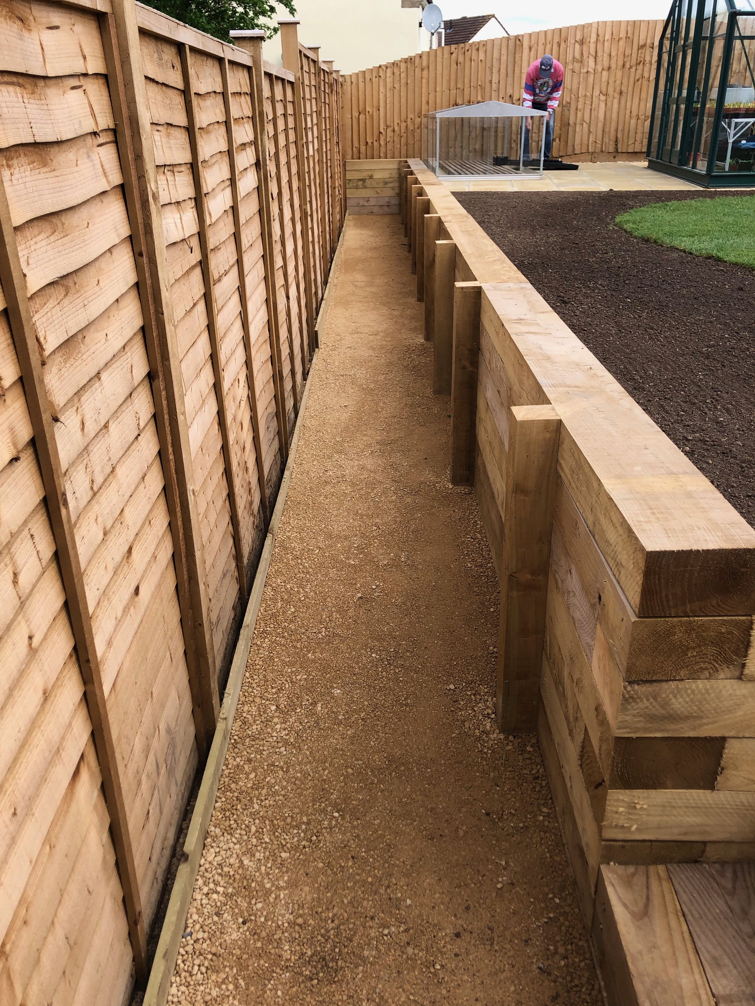A Cotswold path-gravel (hoggin) is compacted to create a solid and low-maintenance path along the bottom of the wall, with steps down from the lawn. A new planting border is created at the top.