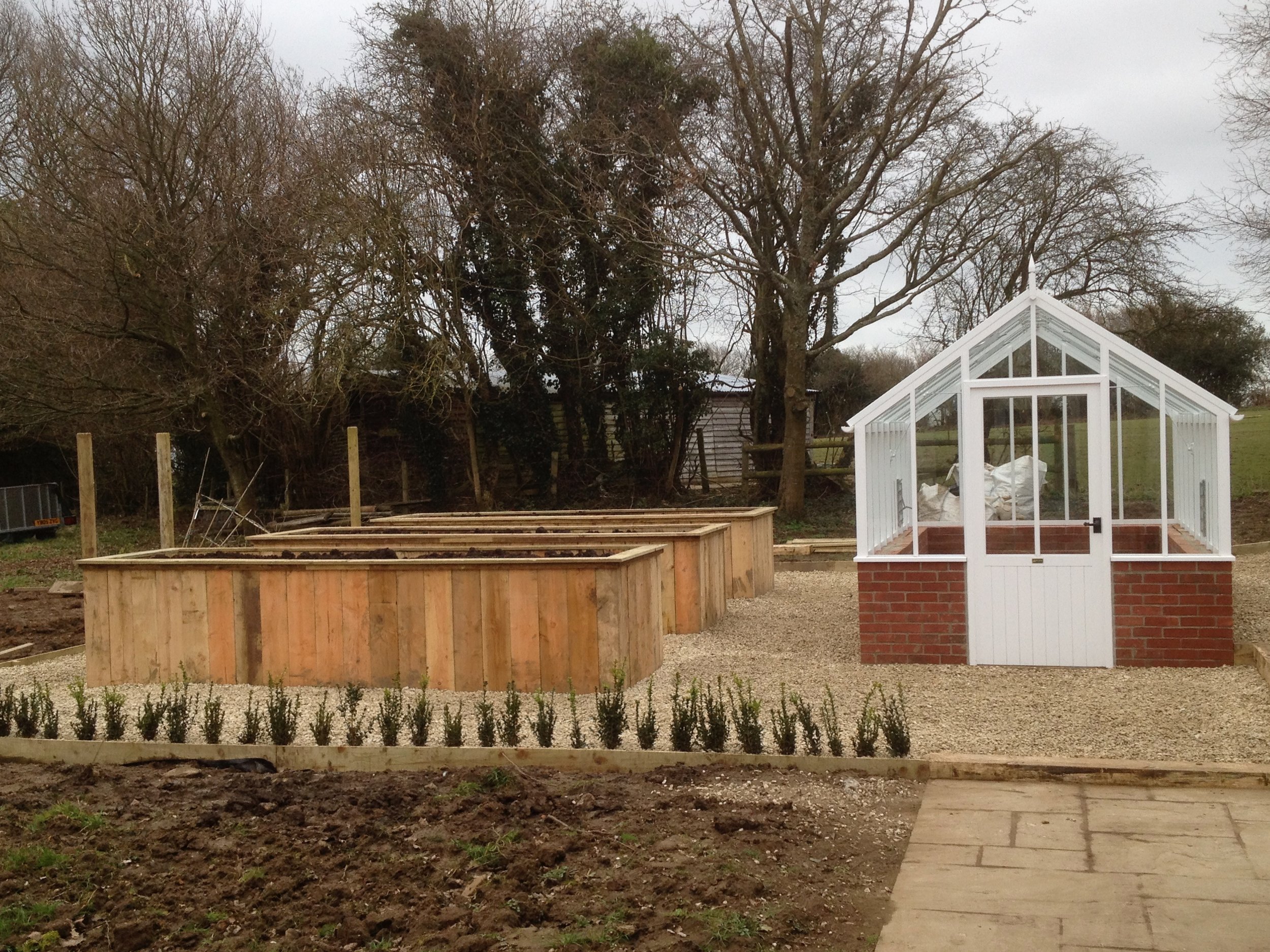 The client here requested high raised beds and Green & Gorgeous came up with this design, using a traditional greenhouse, with very untraditional raised beds! Larch sleepers were installed vertically making these beds a really striking feature.