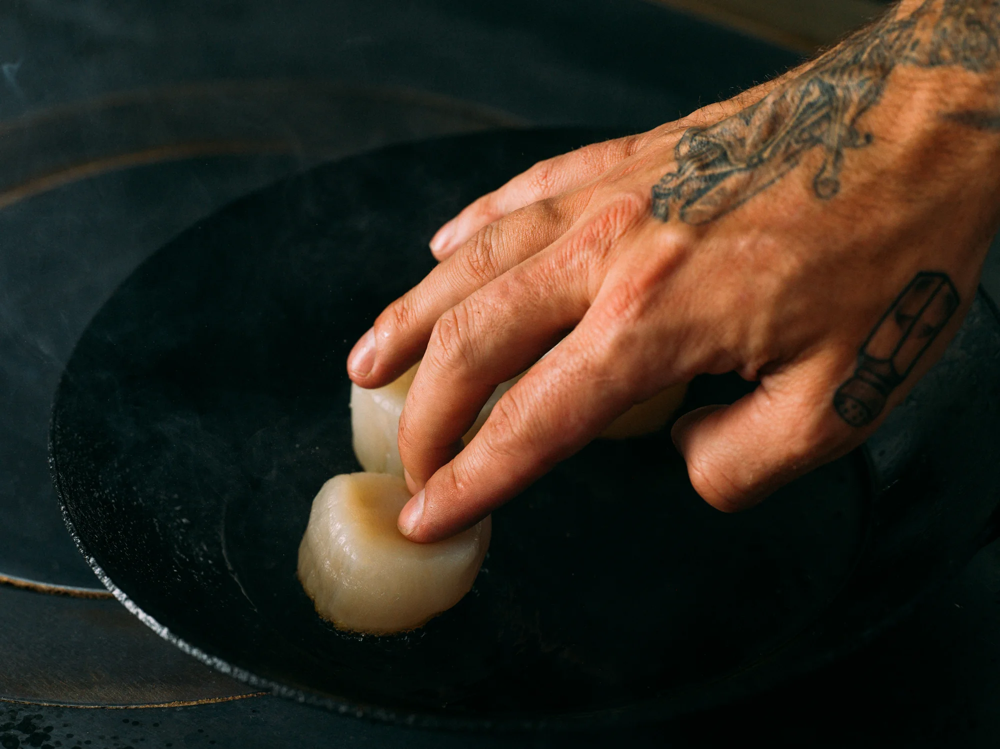 Chef preparing food in a heated pan.