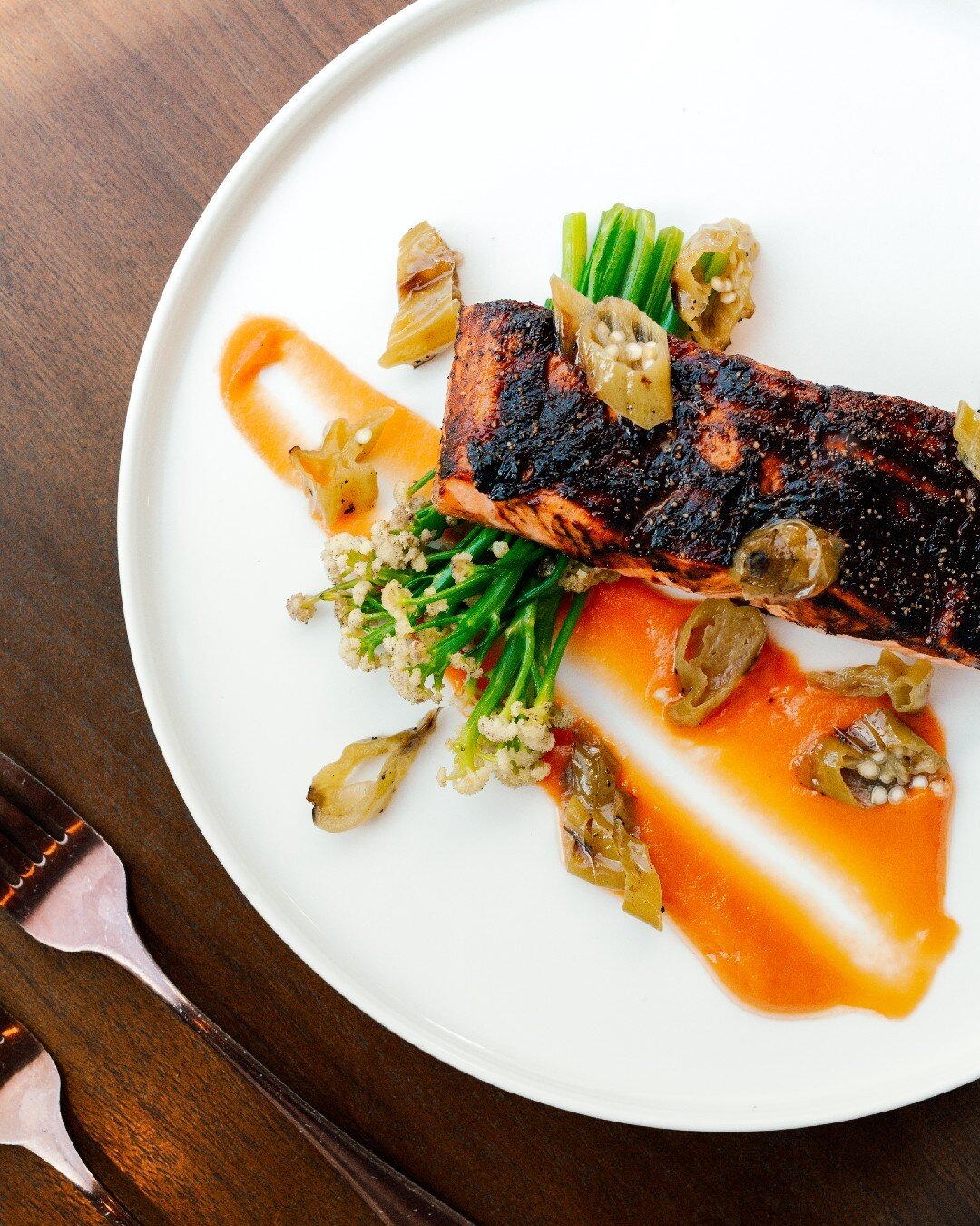 Experience the ultimate culinary delight with our King Salmon dish. Savor a perfectly cooked salmon fillet served with a rich miso carrot puree, spiced ginger baby cauliflower, and tangy pickled shishito peppers.