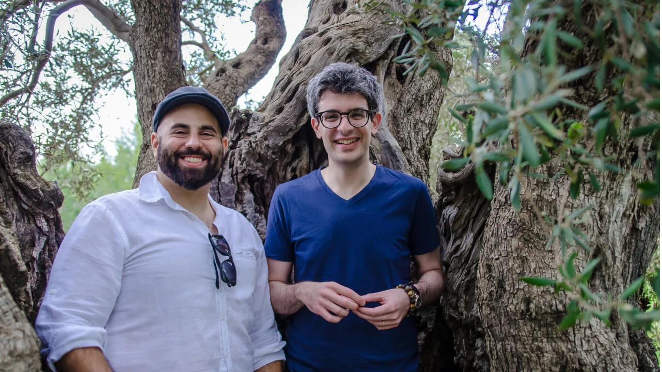 Alex and Hasan, a greek Cypriot and a Turkish Cypriot inside an olive tree holding olives and smiling.jpg