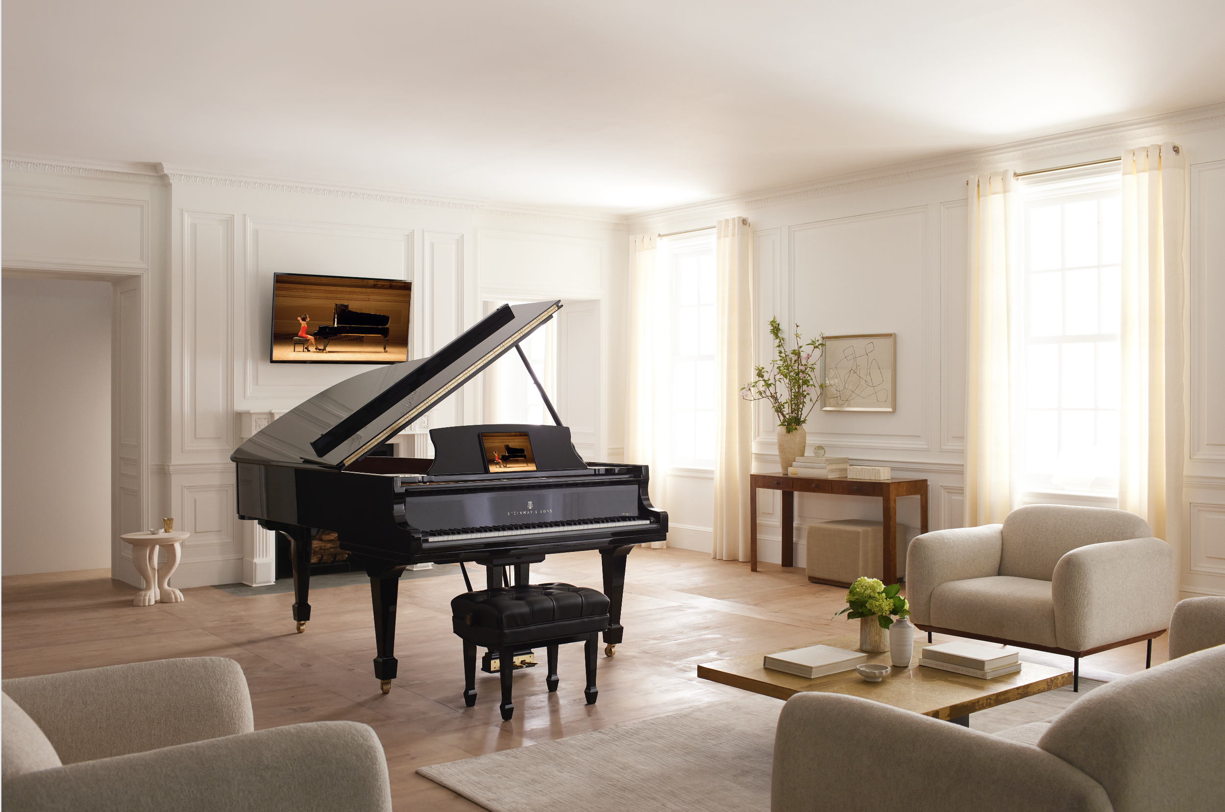 Sala de estar con un piano vertical negro en el centro y un televisor en la pared. Muebles de color beige, cortinas claras y una mesa de madera con libros y plantas decorativas.