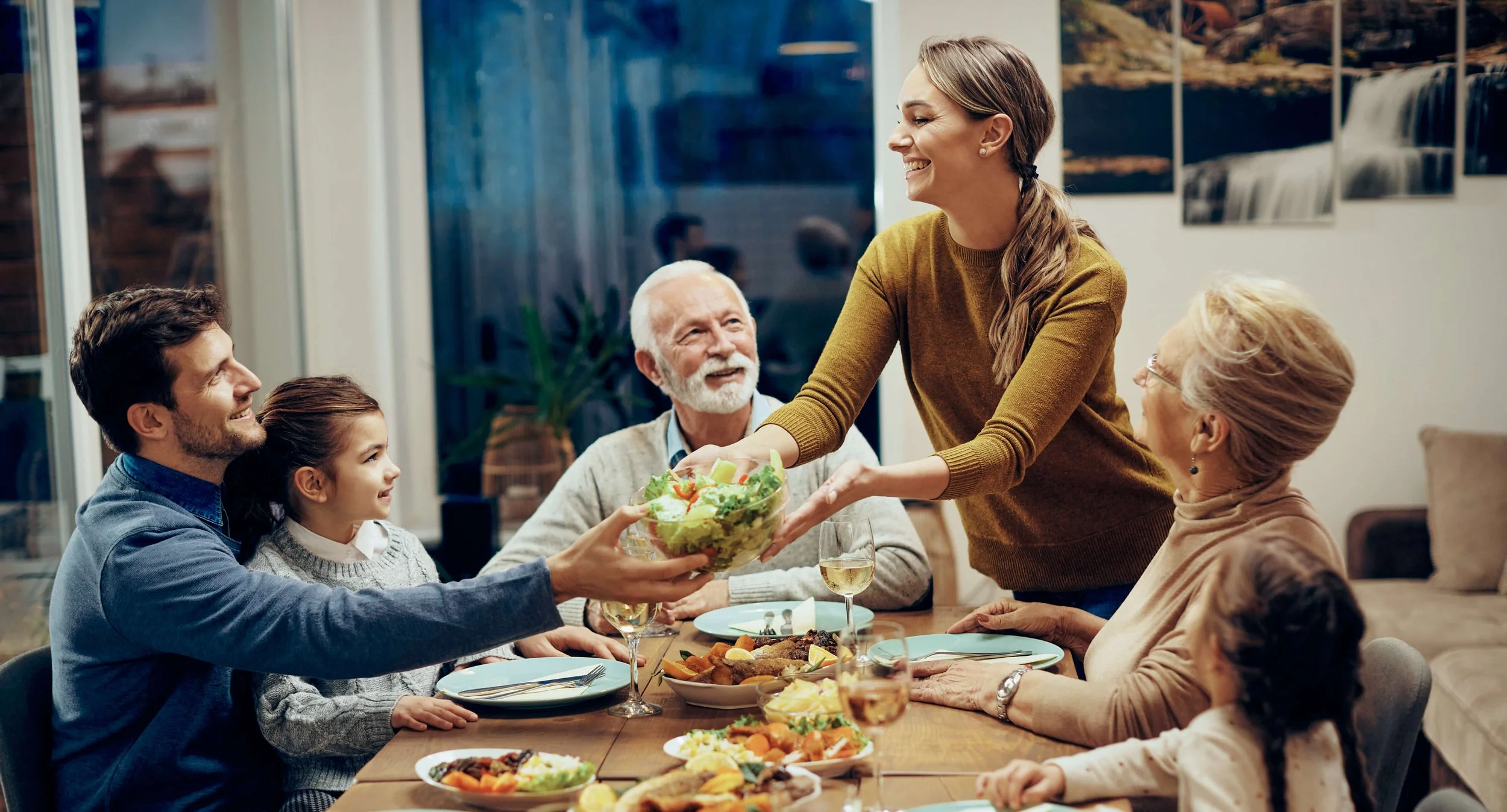 A picture of a happy family having dinner. Three generations sit at the table enjoying themselves.