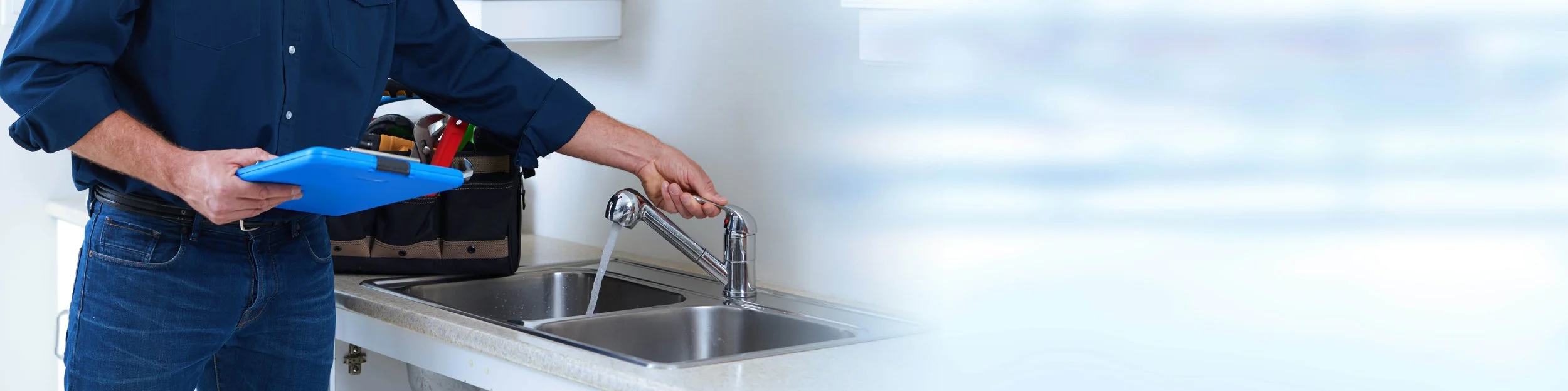 A picture of a plumber working on a kitchen faucet with fresh running water.