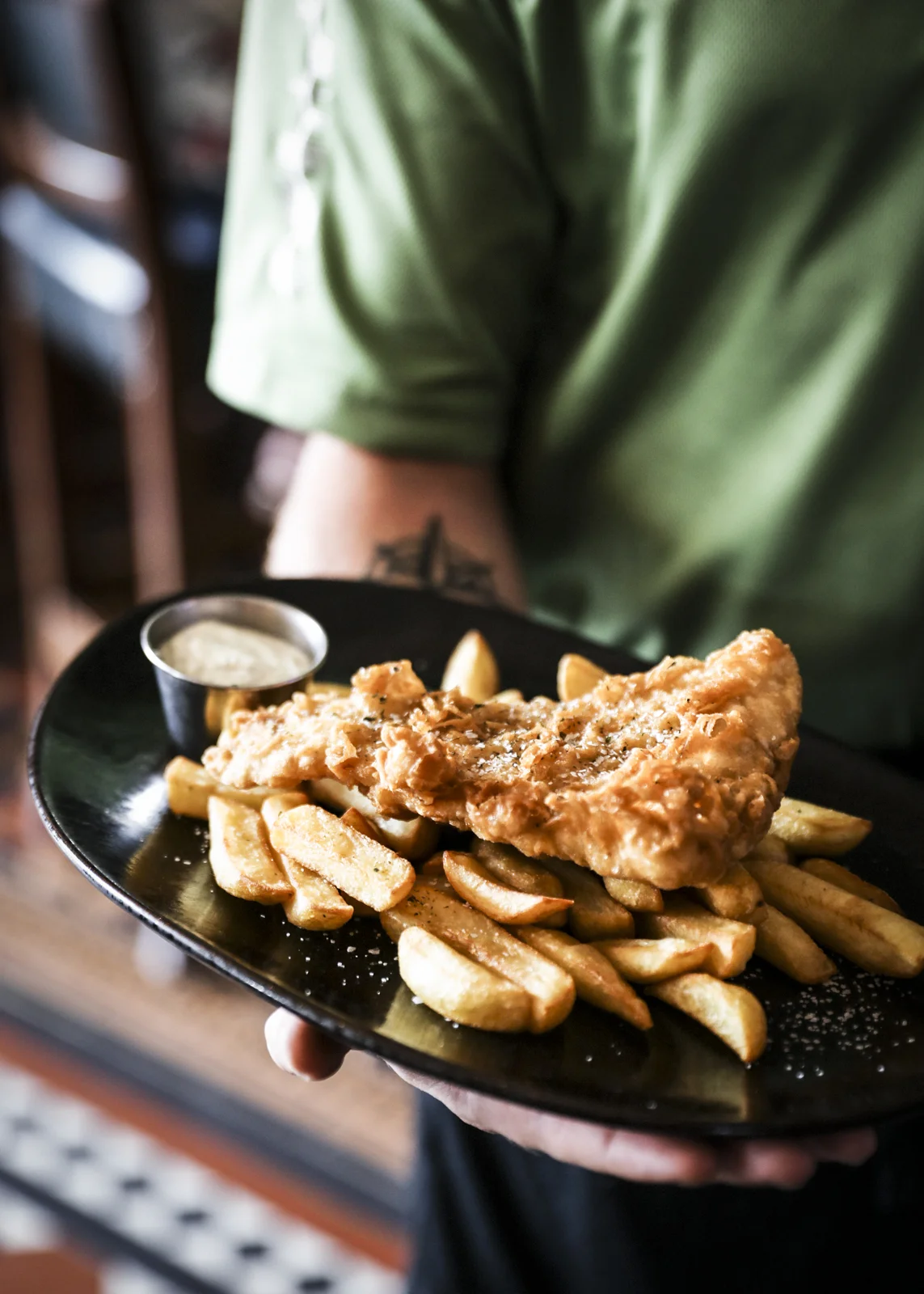Person holding plate of fish and chips