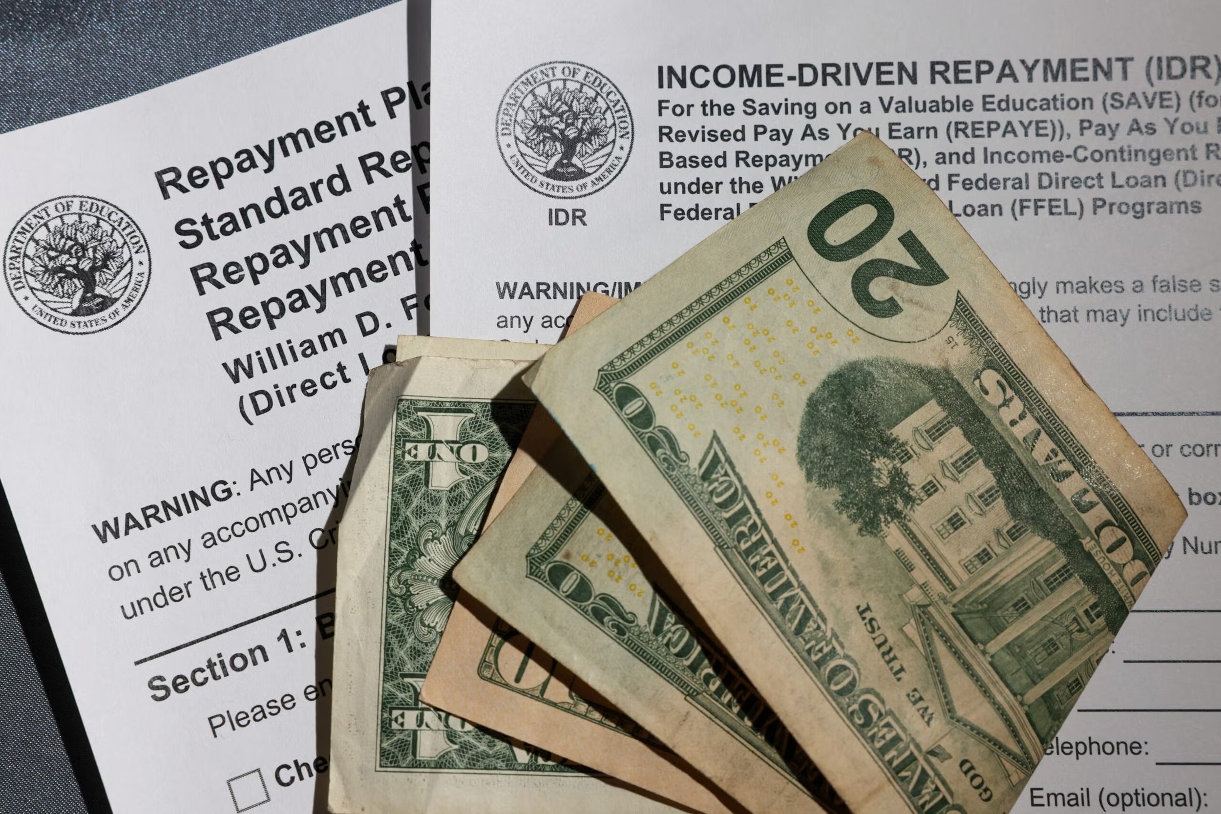Close-up of U.S. dollar bills placed on top of a tax document related to income-driven repayment plans.