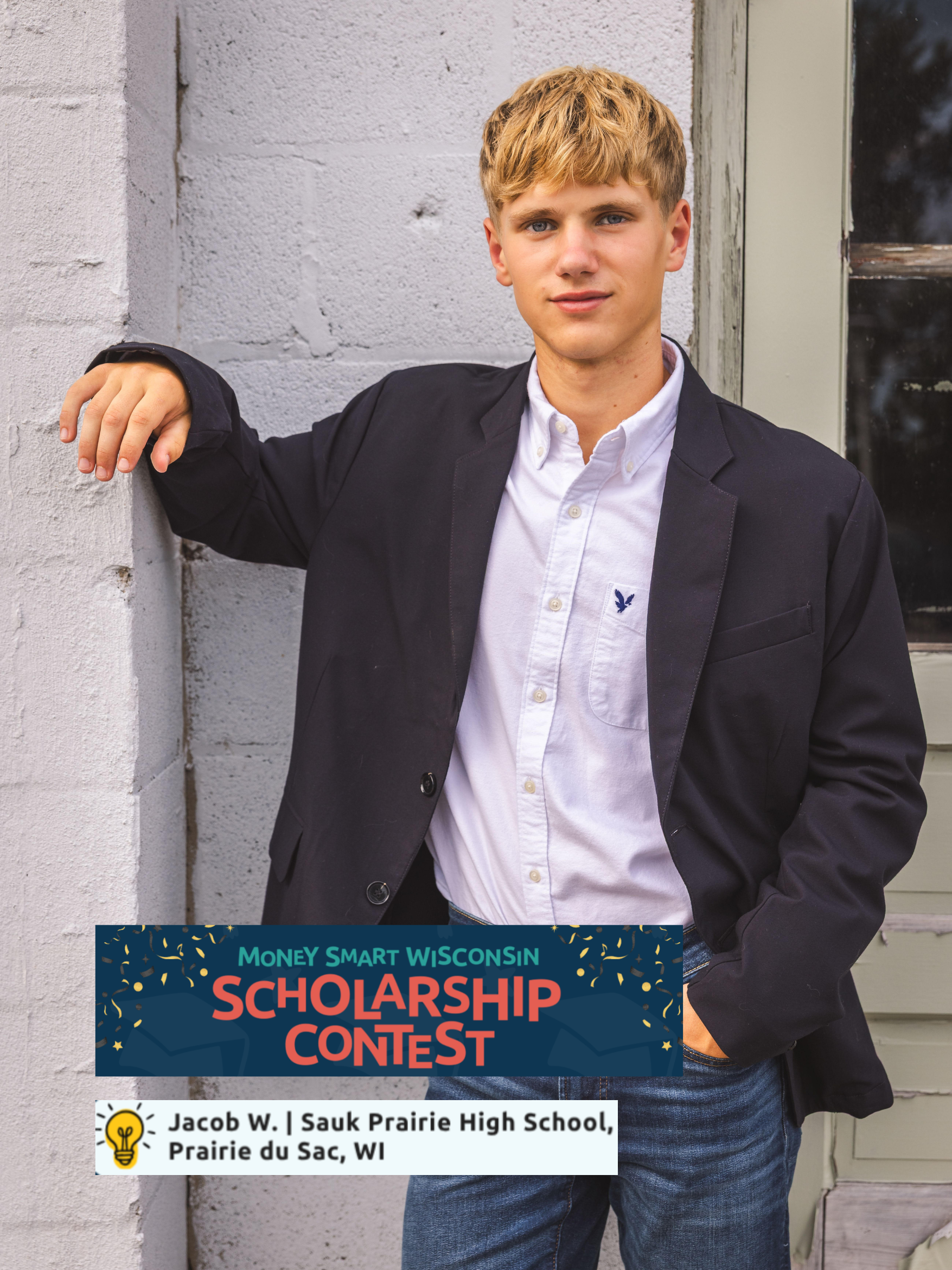 A young man with blond hair and blue eyes wearing a white shirt and a black blazer standing against a white brick wall, with a window to his right, and a scholarship contest advertisement overlapping part of his waist.