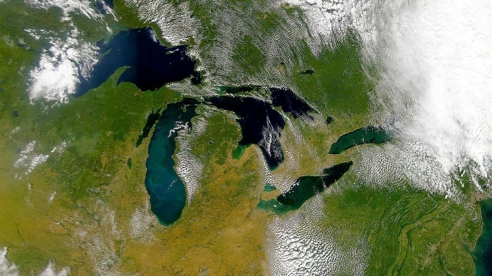 Satellite image of the Great Lakes and surrounding regions in North America, showing lakes, land, and cloud cover.