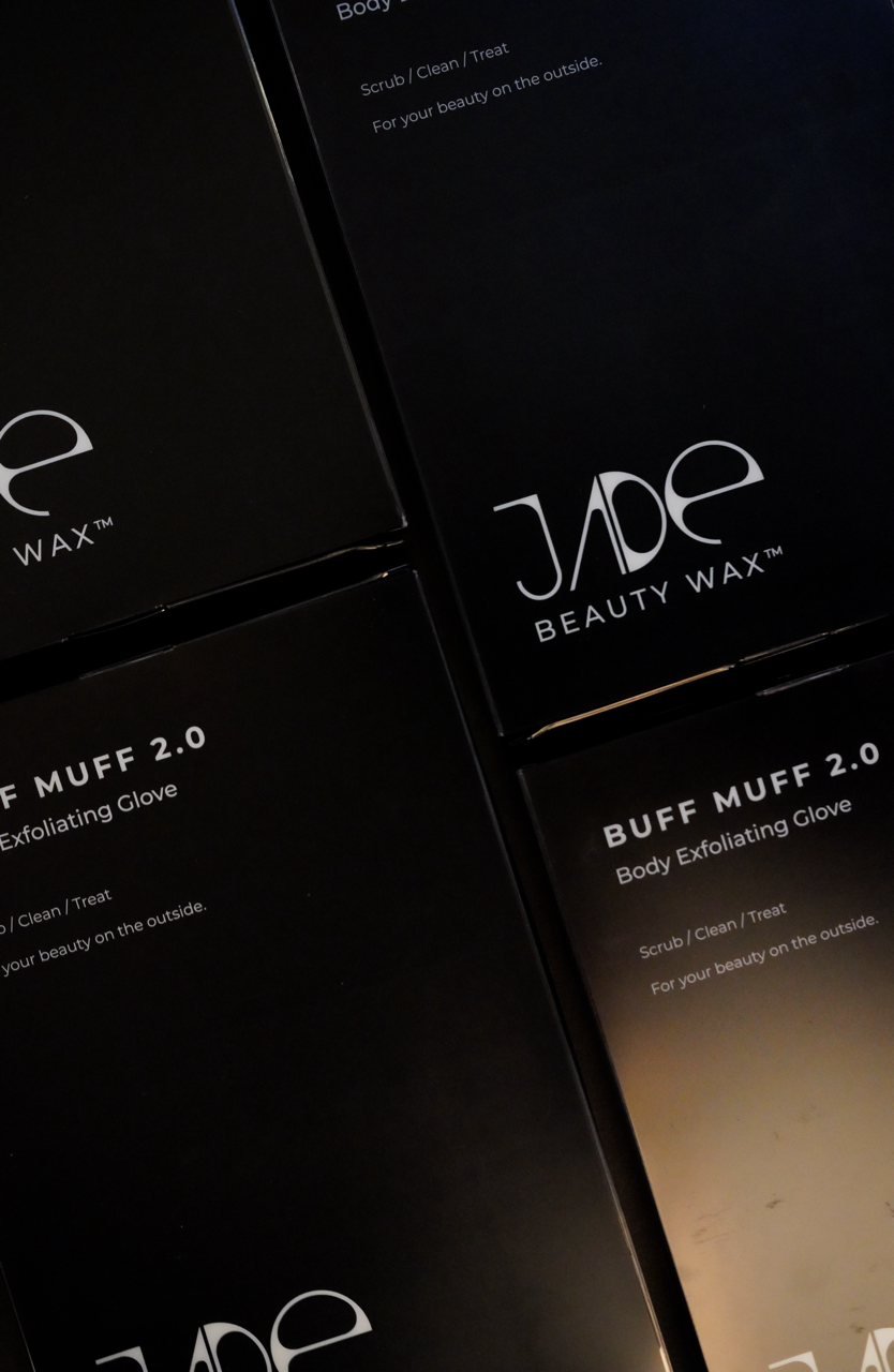 Two black boxes with white text displaying JADS Beauty Wax Buff Muff 2.0 Body Exfoliating Glove, with a partial view of a third box above.