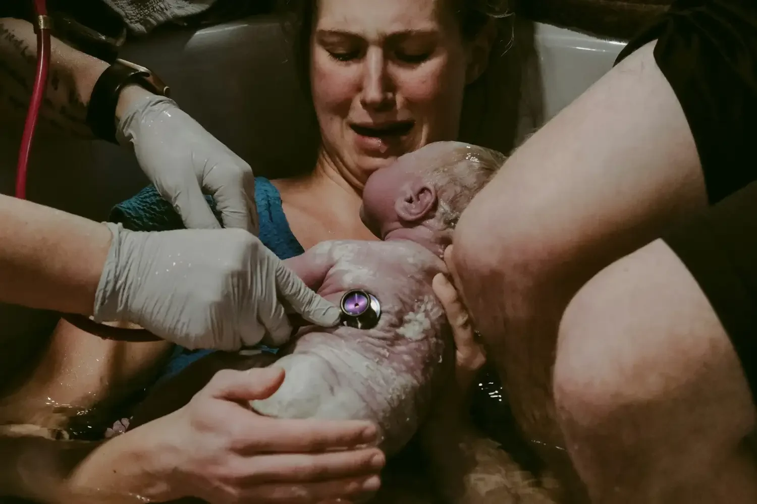 A woman giving birth to a baby in a hospital. Medical staff assist during labor, and the woman looks emotional.