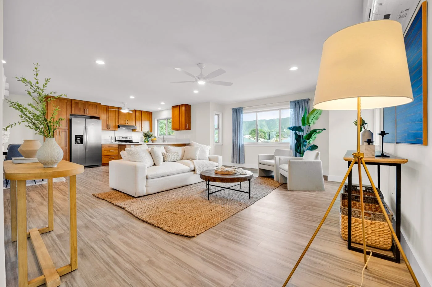Open-concept living and kitchen area staged by OASIS STAGING + DESIGN with warm wood cabinetry, neutral furniture, and mountain views