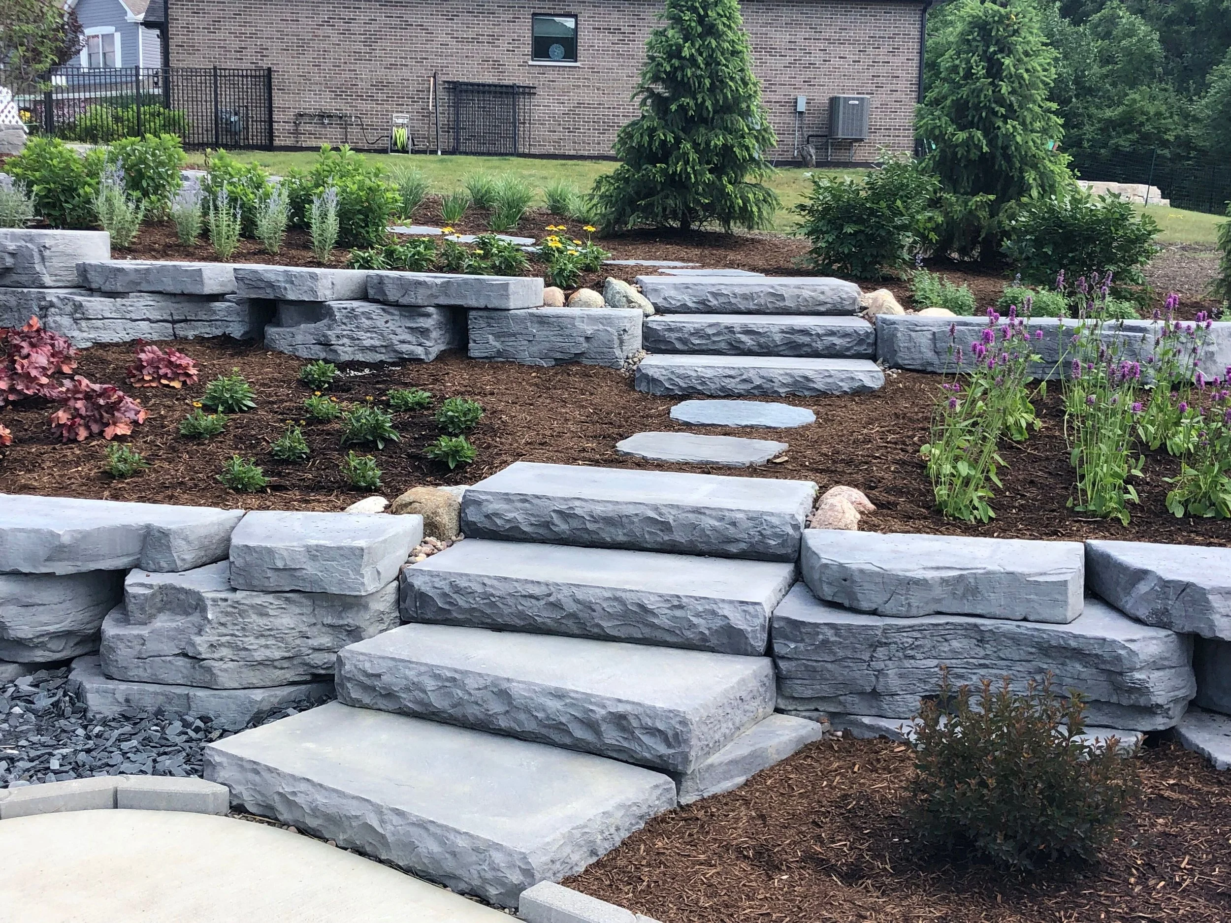 How a Retaining Wall and Plantings in St. John, IN, Can Transform Your Backyard Into a Level, Usable Space