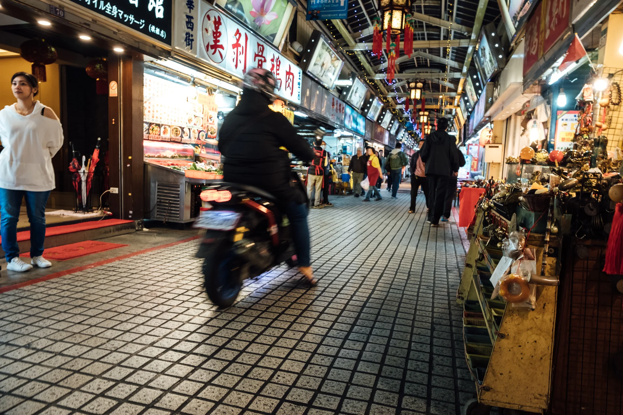 Scooters are still a common sight even in crowded narrow night market alleys.