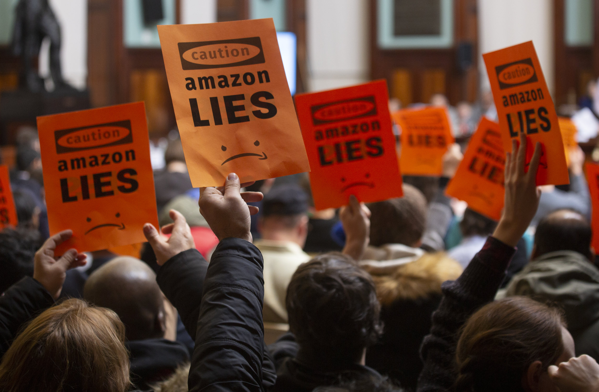 Protesters Hold Up Signs During City Council Hearing Regarding Amazon HQ2