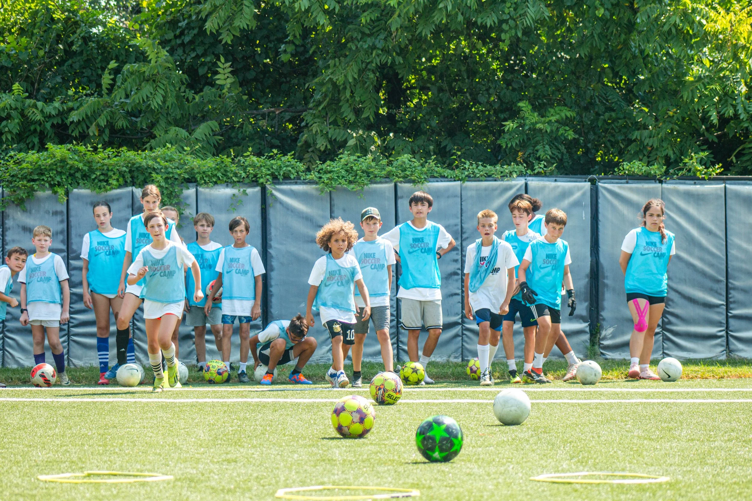 Two boys running on a soccer field during practice, with another boy in the background.