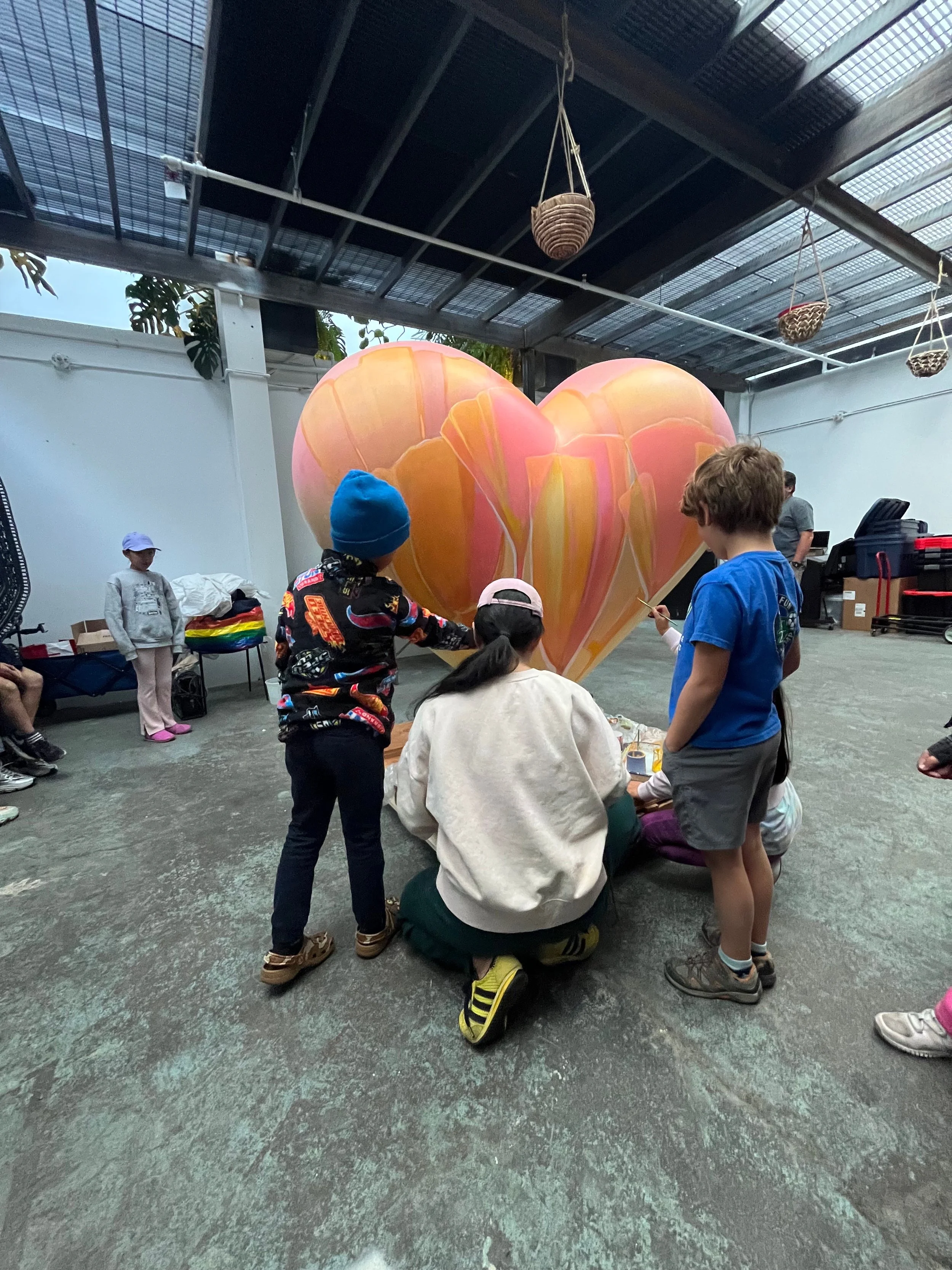 Community members painting the SŌL heart sculpture with Dev Heyrana at her Ciel Creative Space studio in Berkeley, California, a commission for the San Francisco General Hospital Foundation
