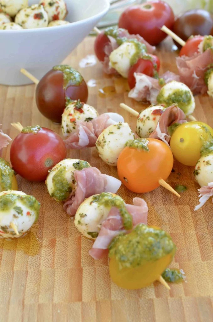 Caprese Skewers with Marinated Mozzarella, Tomatoes, Prosciutto, and Lemony Basil Pesto