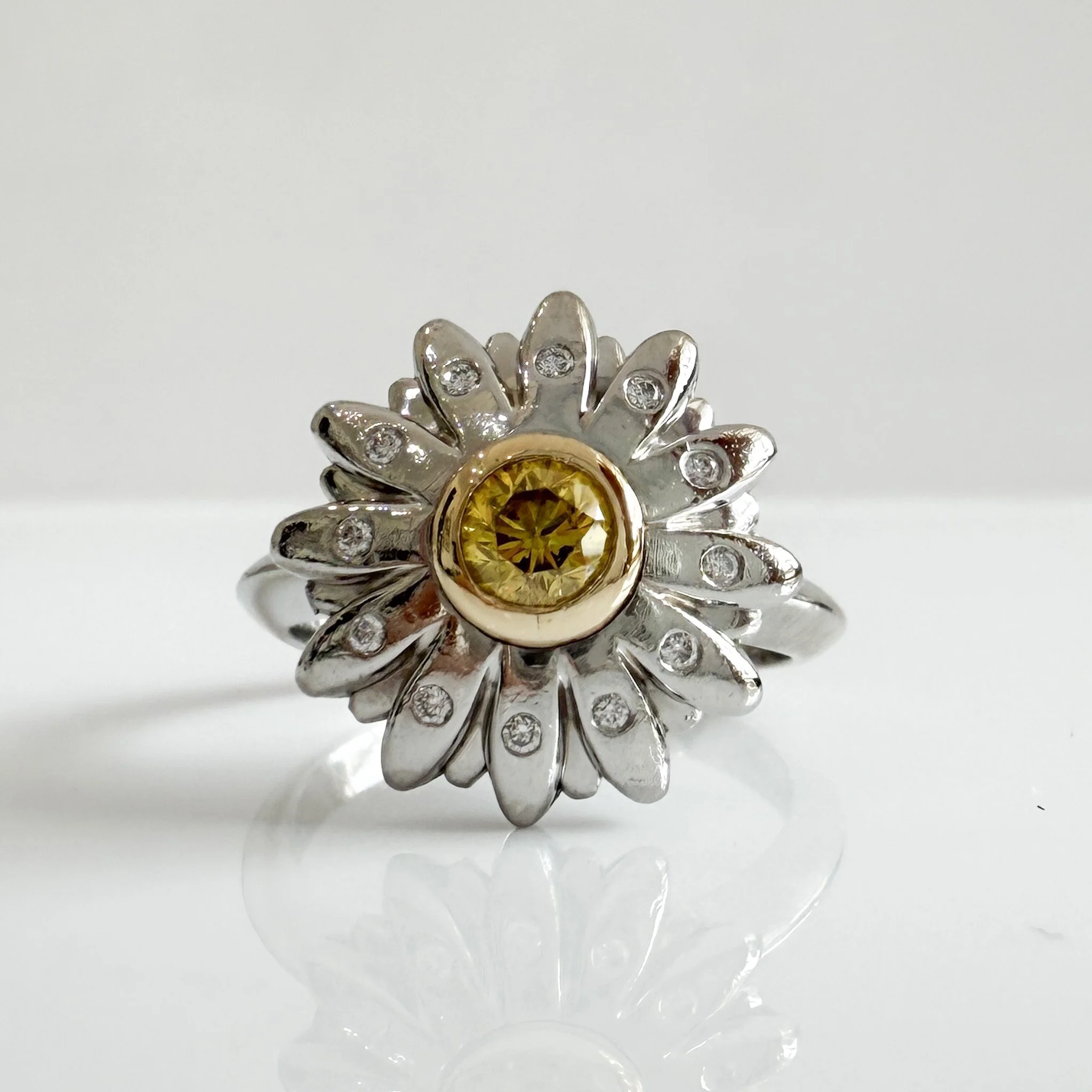 #ThrowbackThursday ✨

Every so often a design comes along that completely captures the imagination. This beautiful daisy engagement ring was handmade in platinum and features a bold yellow diamond at its centre with flush set diamonds sparkling on ea