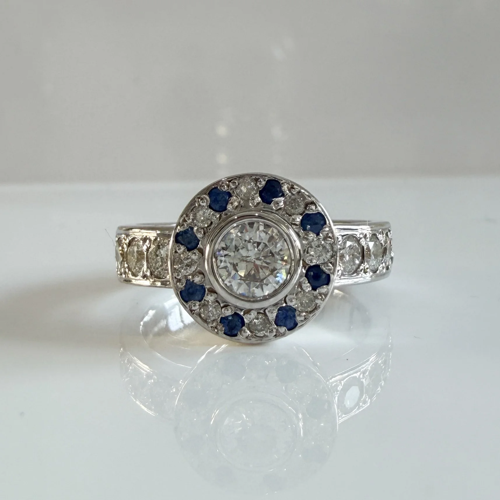 Teresa visited us wanting to reimagine her white gold rings into something fresh and creative. She was drawn to the idea of a halo-style ring, blending her own diamonds with striking new blue sapphires for a vibrant, personal touch.

After exploring 