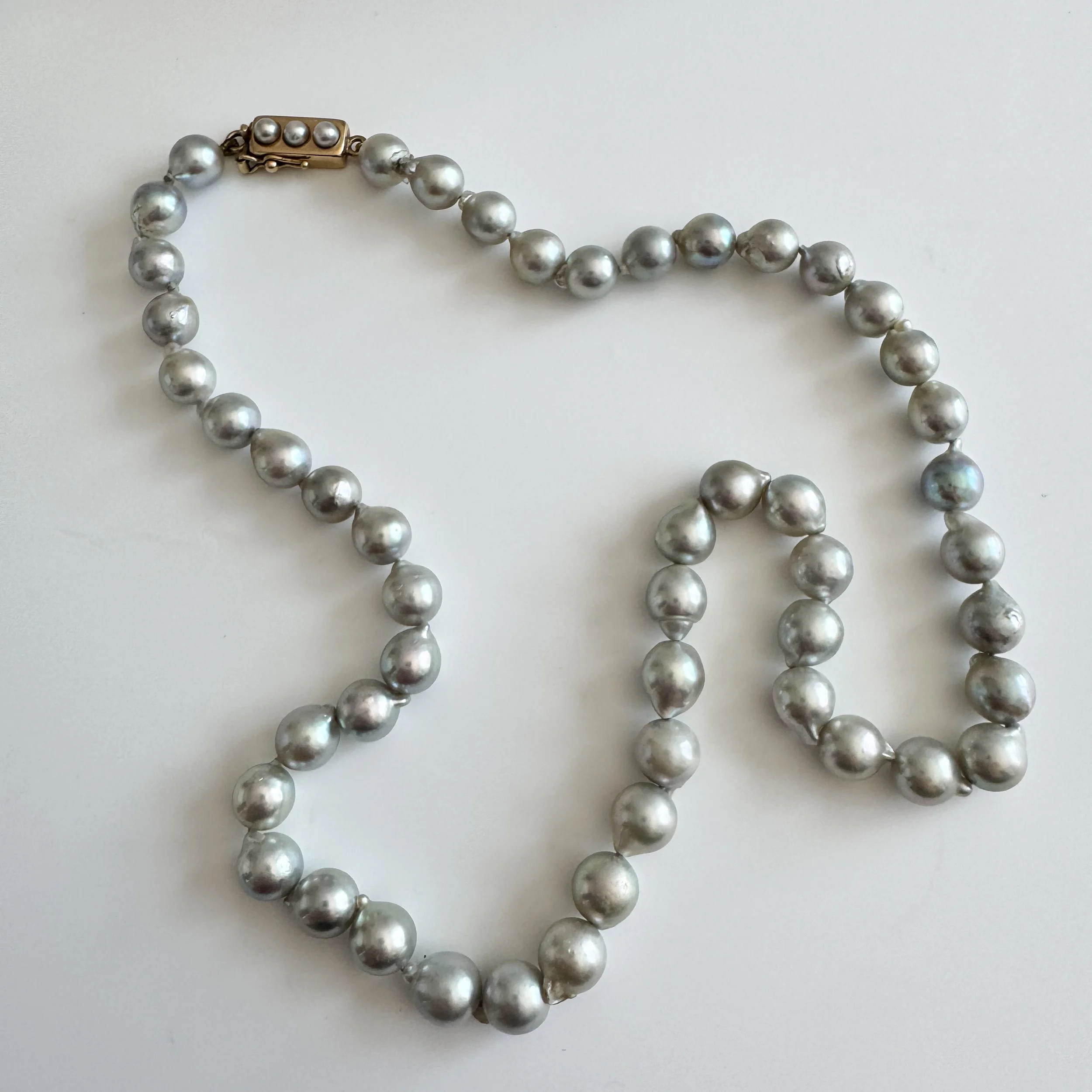 The pearl necklace lying down so the full necklace is in view with the clasp at the top