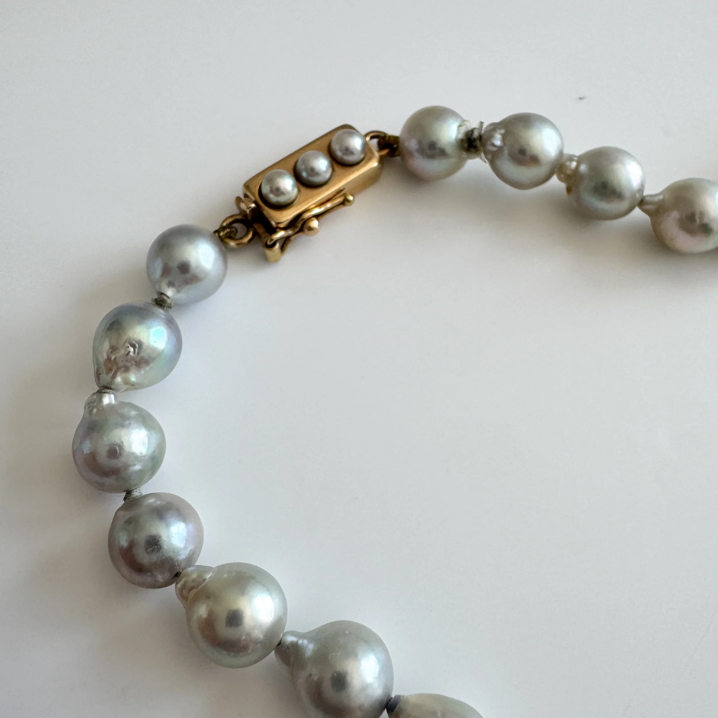 A close up photo of the clasp. It is a gold rectangular clasp with three small pearls on the rectangular clasp