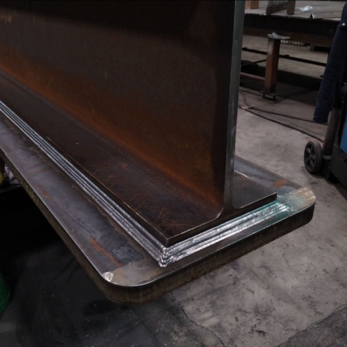 Heavy multipass weld joining a vertical structural steel plate during bridge fabrication.