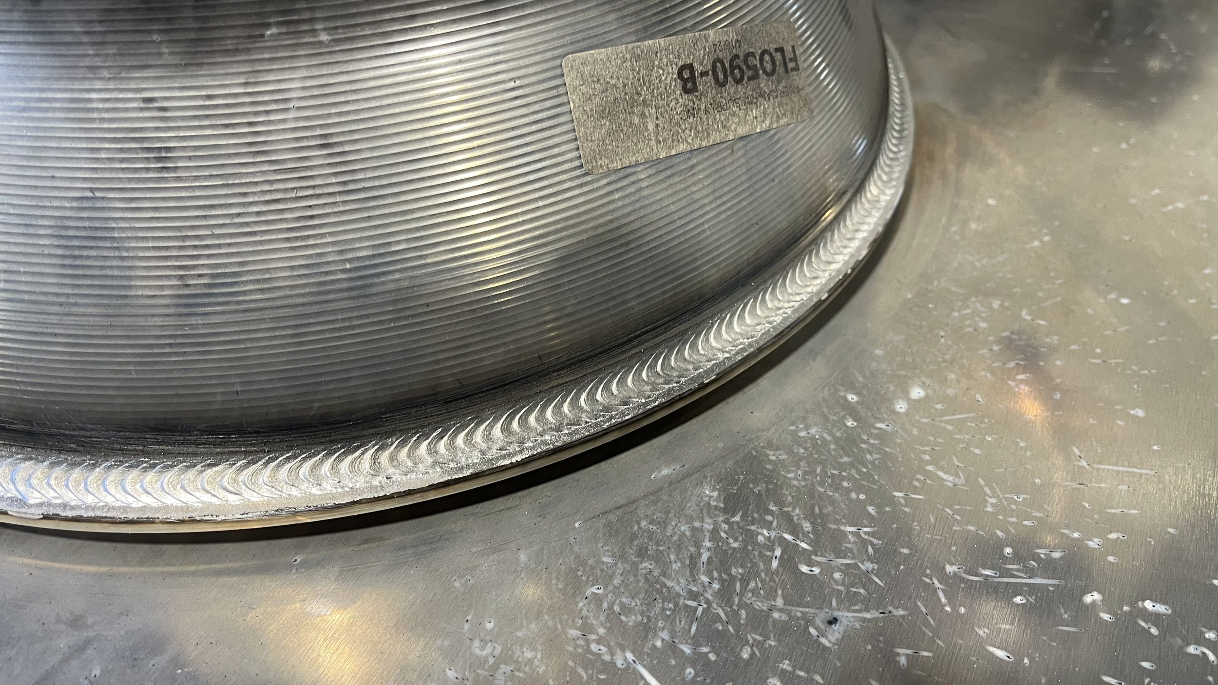 Close-up of a precision aluminum weld with a uniform bead profile and clean edges on a fabricated cylindrical component.