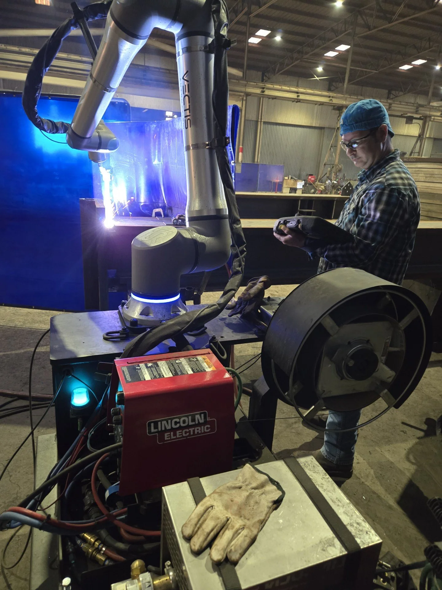 Operator monitors a Vectis cobot welding a structural steel joint at Central Texas Ironworks.