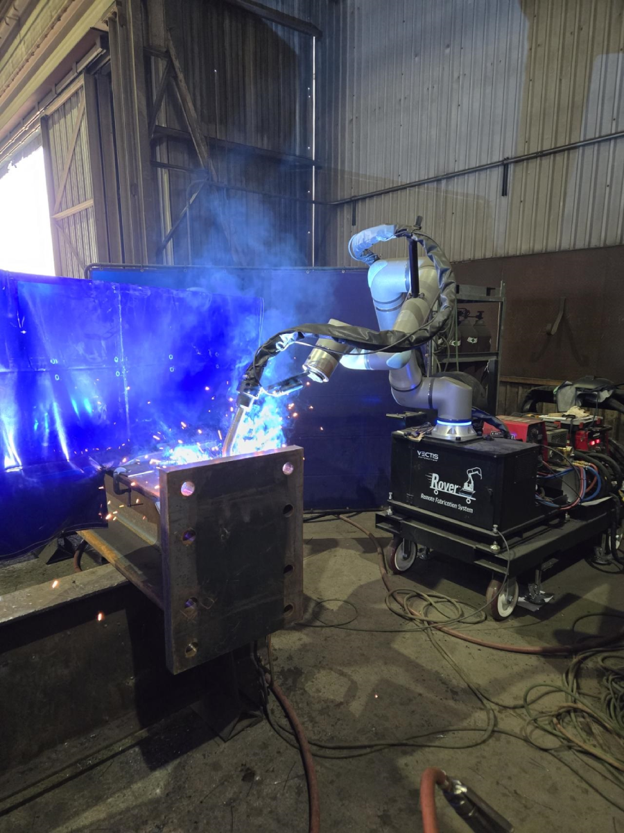 Mobile cobot welding system performing an automated weld on a large steel fabrication component in a manufacturing shop.