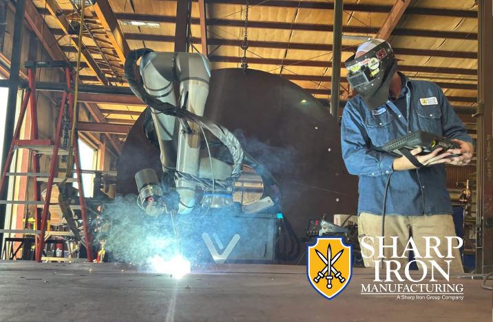 Vectis cobot welding system performing a weld while an operator monitors the process at Sharp Iron Manufacturing.