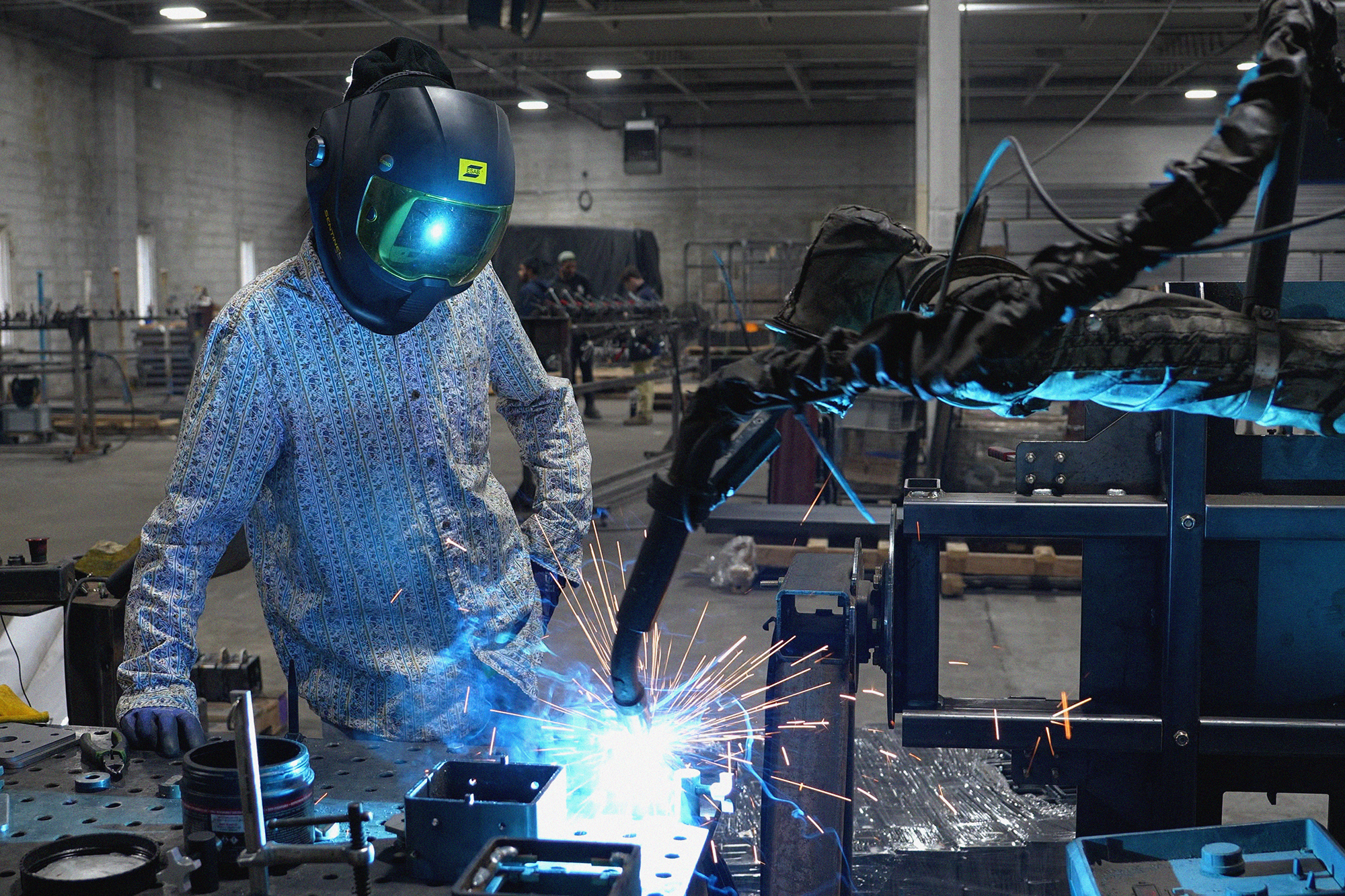 Caltech Cobot Champion Owen Doran observes a Vectis cobot running a new weld program at a fixture table.