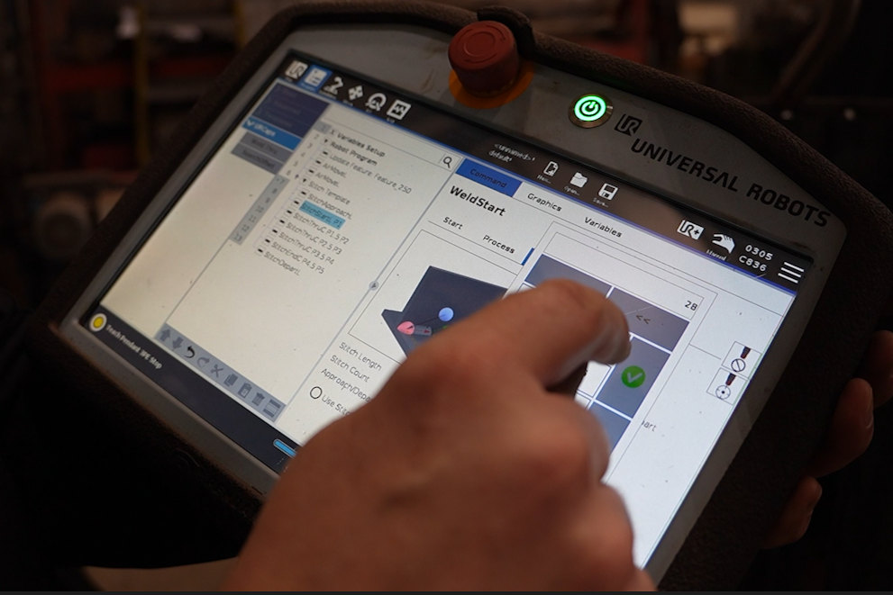 Operator uses the touchscreen controls for a Vectis cobot welding system at KYJO Steel.