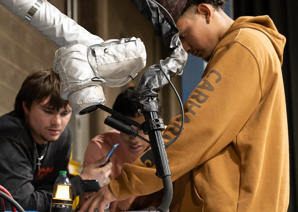 Young CM Welding team member learning to operate a Vectis cobot welding system with support from fellow Cobot Champions.
