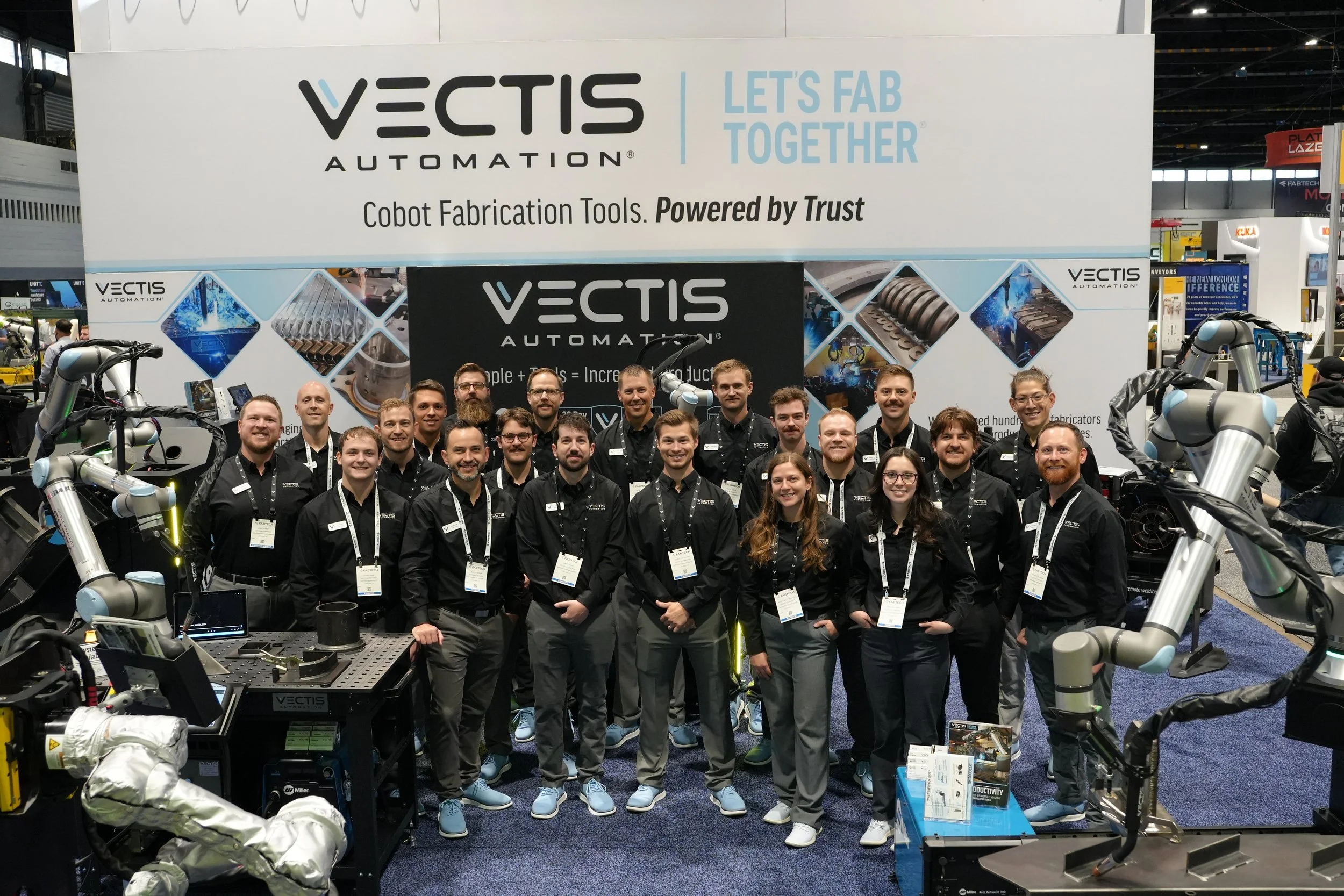 Vectis Automation team standing at the FABTECH booth with cobot welding and plasma cutting systems on display.
