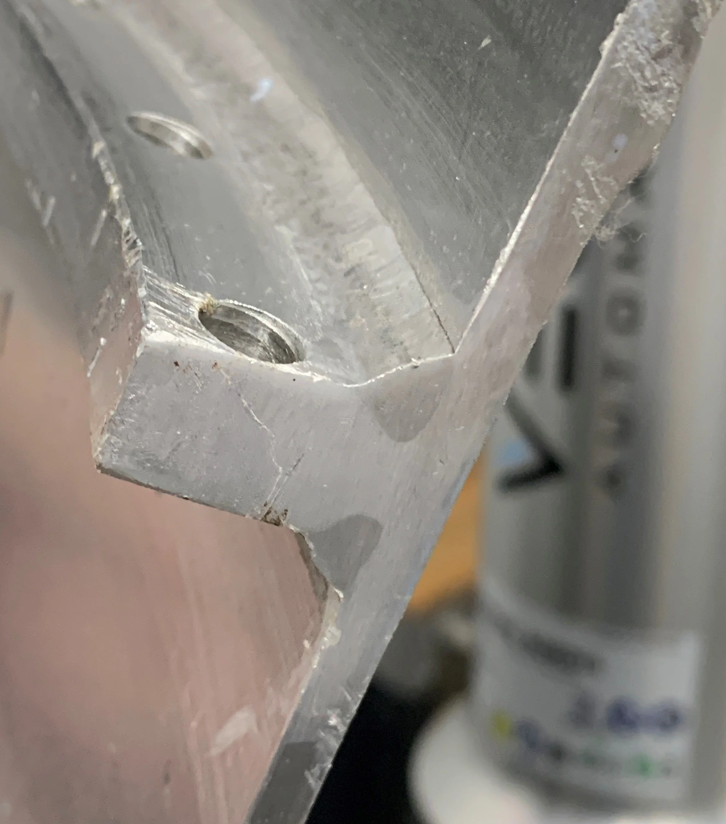 Close-up of an aluminum rim flange with a welded seam and bolt holes, showing weld bead shape, surface finish, and heat marks from a cobot welding process used in precision aluminum manufacturing.