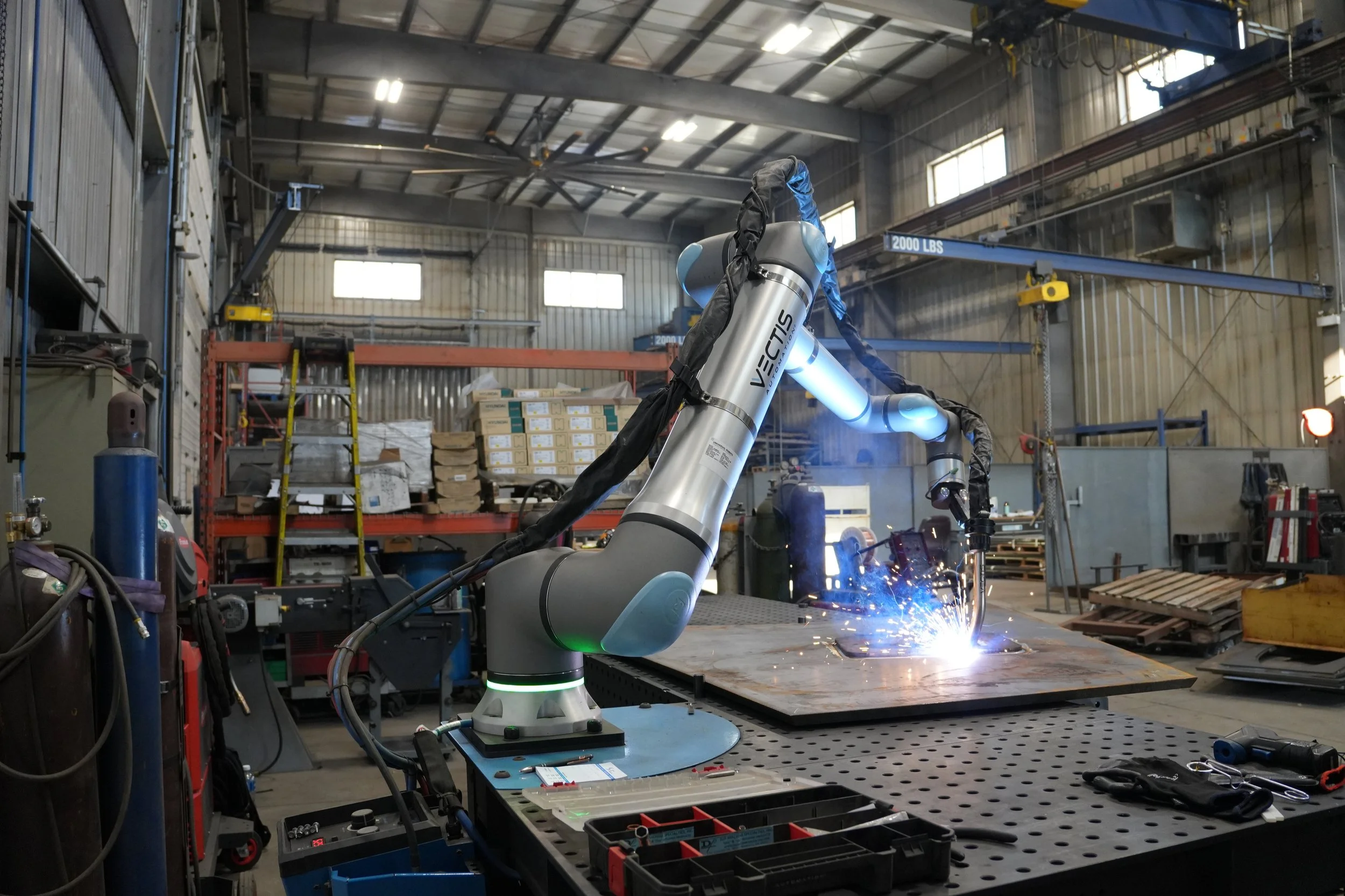 Vectis cobot welding a steel plate on a fabrication table at KYJO Steel.