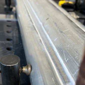 Weld seam on a fabricated aluminum light pole, showing a consistent weld bead along the length of the component.