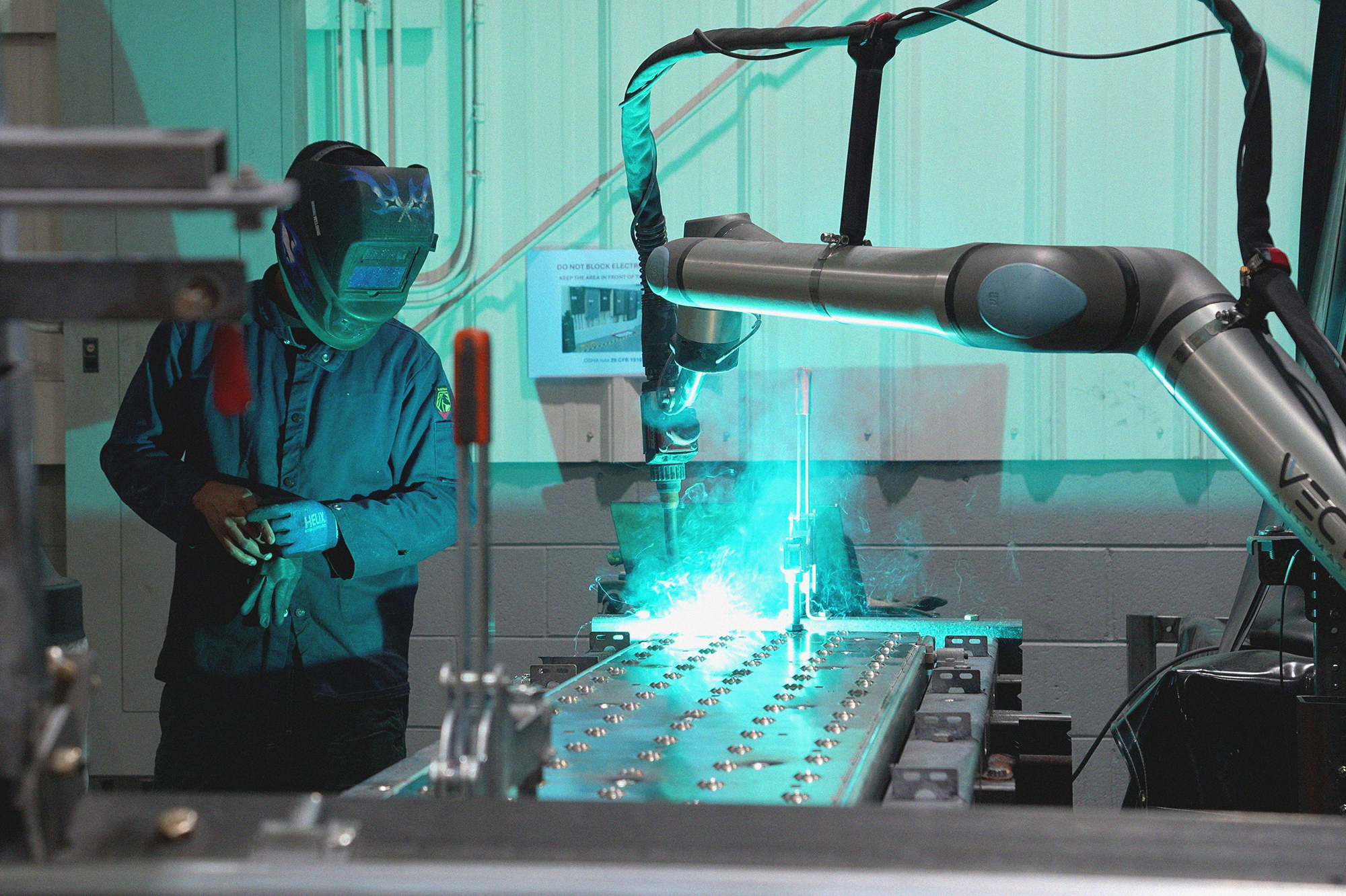 Caltech Manufacturing operator monitoring a Vectis cobot as it MIG welds a repetitive application formerly completed with TIG welding.