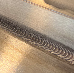 Close-up of a pulse-on-pulse aluminum weld bead with a uniform ripple pattern and consistent weld appearance along the weld seam.