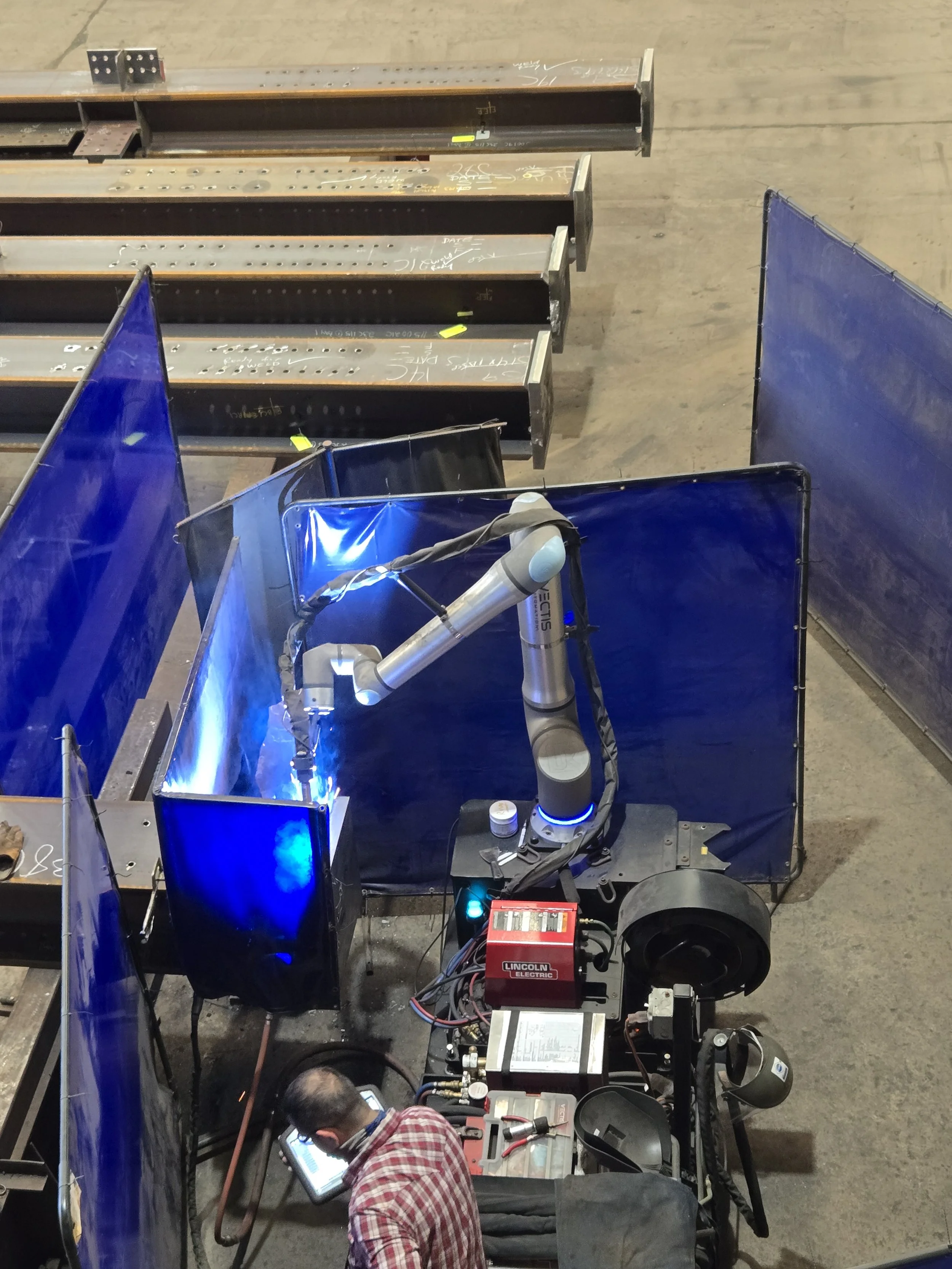 Overhead view of a Vectis cobot welding a structural steel moment joint at Central Texas Ironworks.