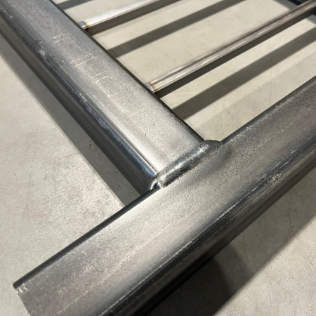 Close-up of a welded square tube joint on a steel handrail fabricated with Vectis Cobot.