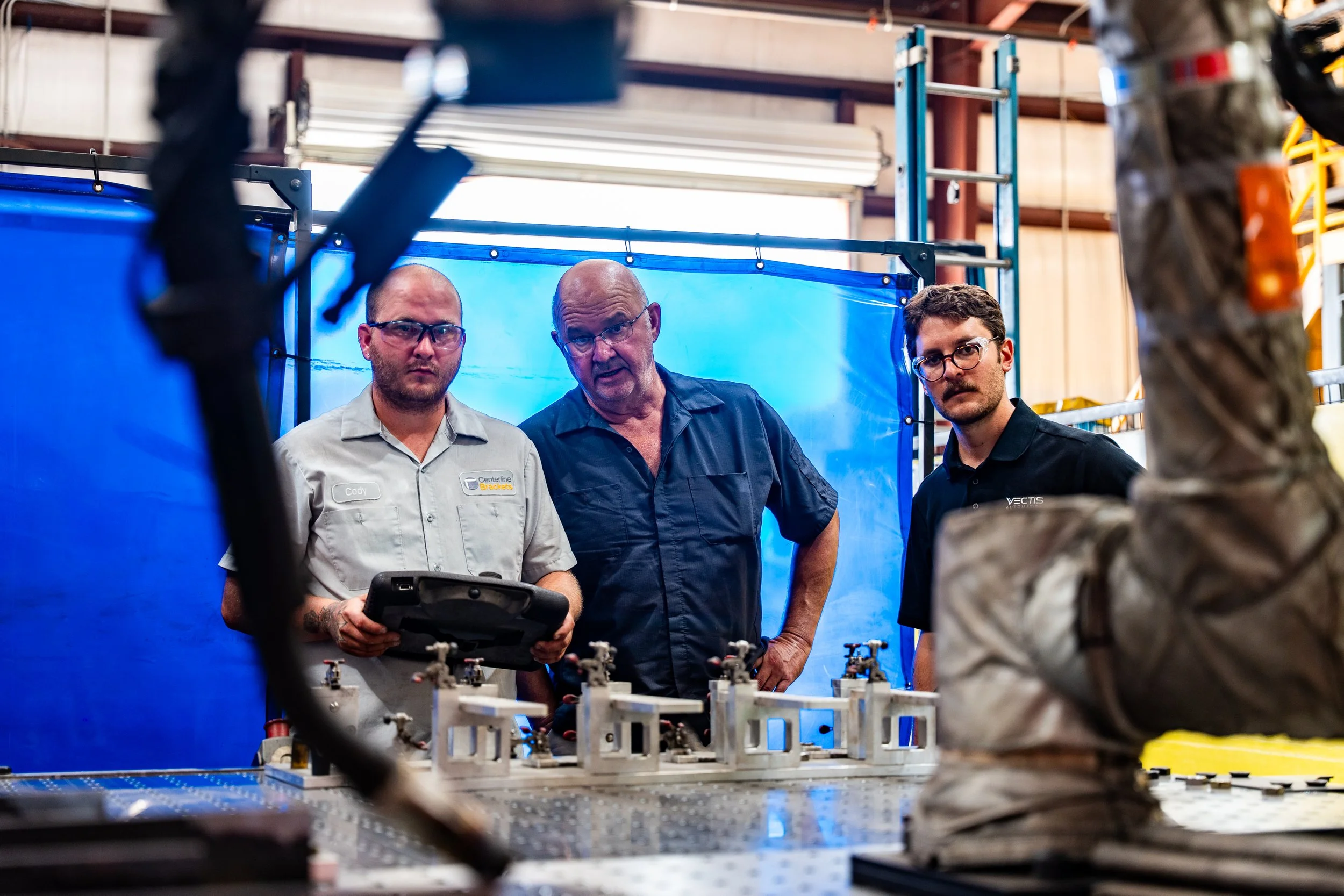 Centerline Brackets and Vectis Automation employees observe welding cobot