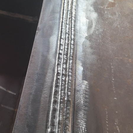 Multipass FCAW weld with multiple vertical passes along a steel joint in the 3G welding position.