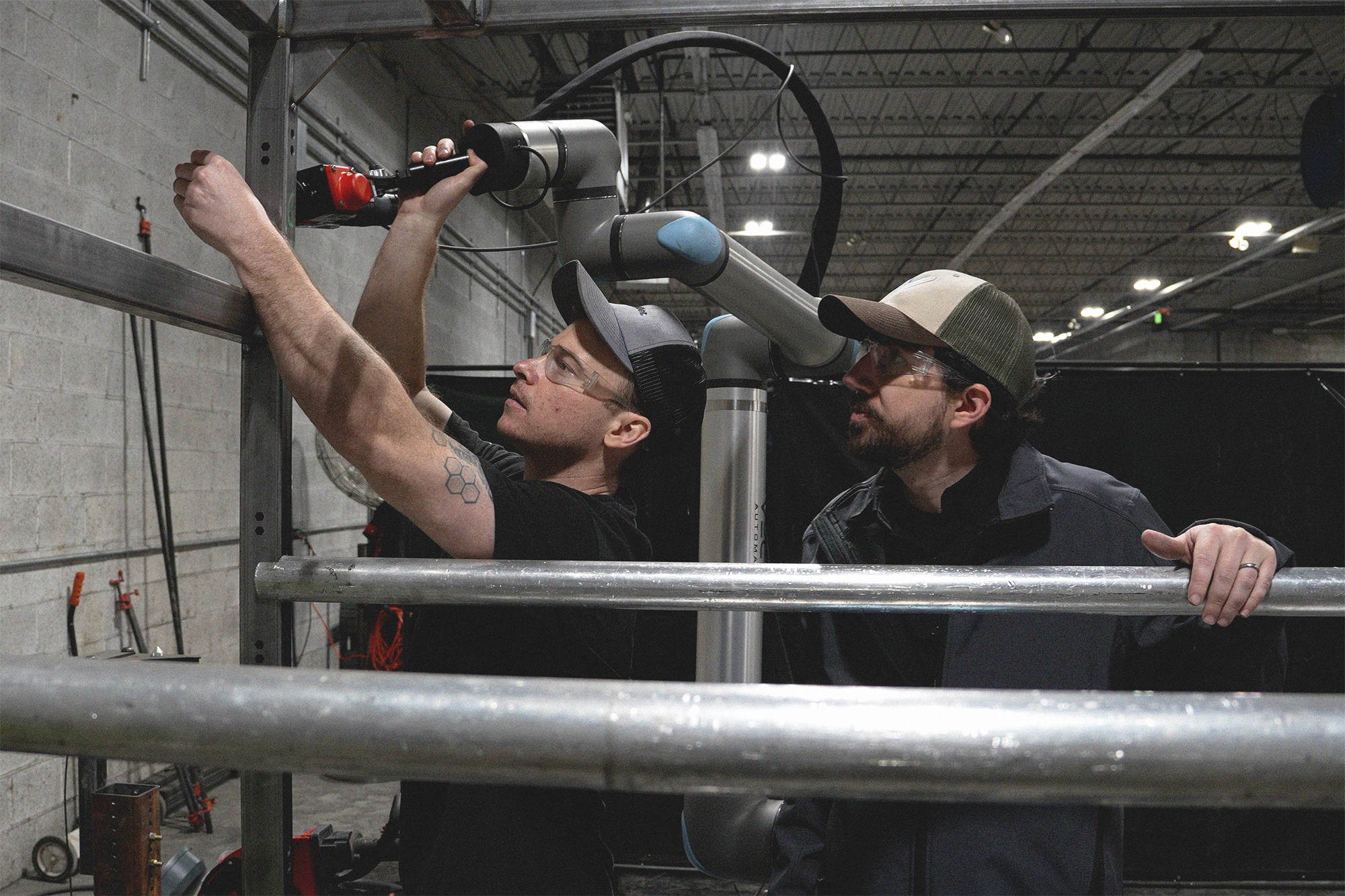 Two Caltech Manufacturing team members position a Vectis cobot welding system for a large metal assembly.
