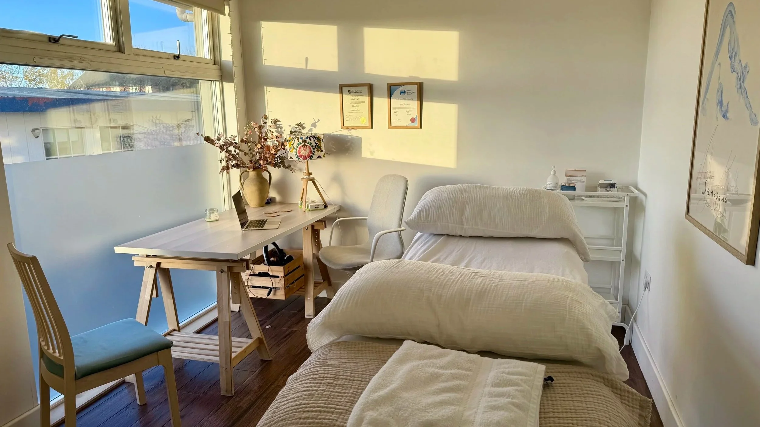 Inside the A D Acupuncture treatment room in the Brockley clinic. Lots of light flooding into acupuncture treatment space with massage couch and desk