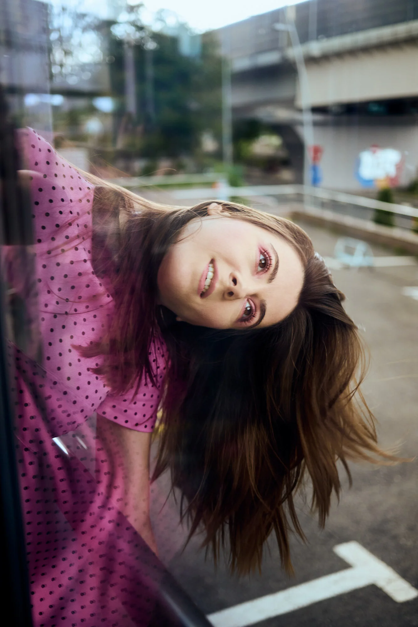 Hanging off a window in a pink dotted dress