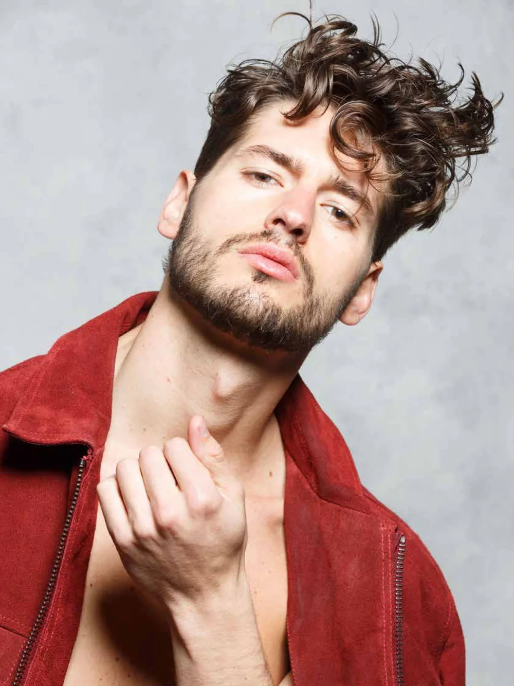 Fashion portrait of a man wearing a red jacket against a gray background