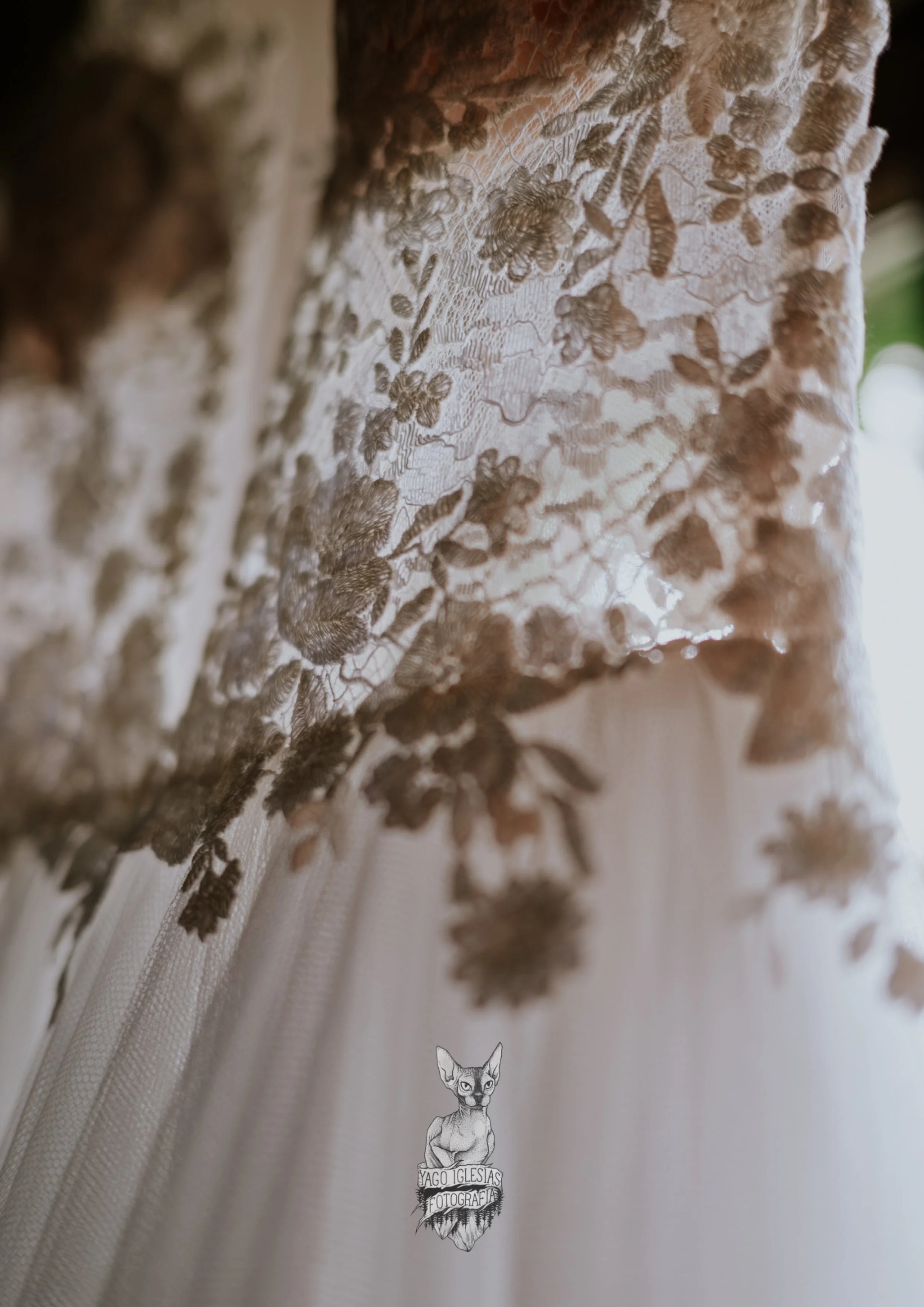 Detalles de encaje en tela blanca con patrón floral y mariposas en tonos beige.