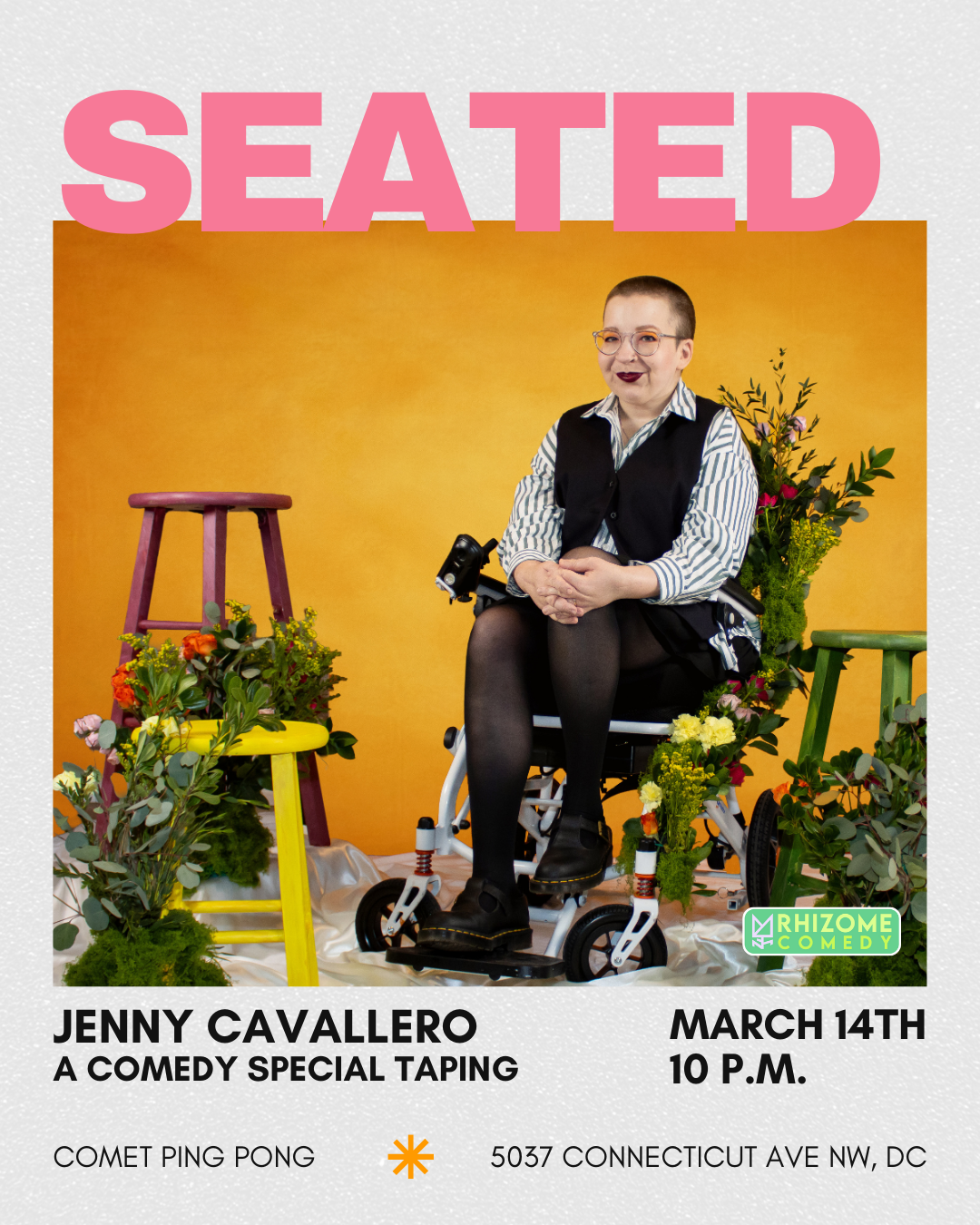 Jenny Cavallero, a white femininie person with a shaved head sits in her wheelchair, which is covered in greenery and flowers. 3 brightly painted stools of various heights surround them with similar plant-life.